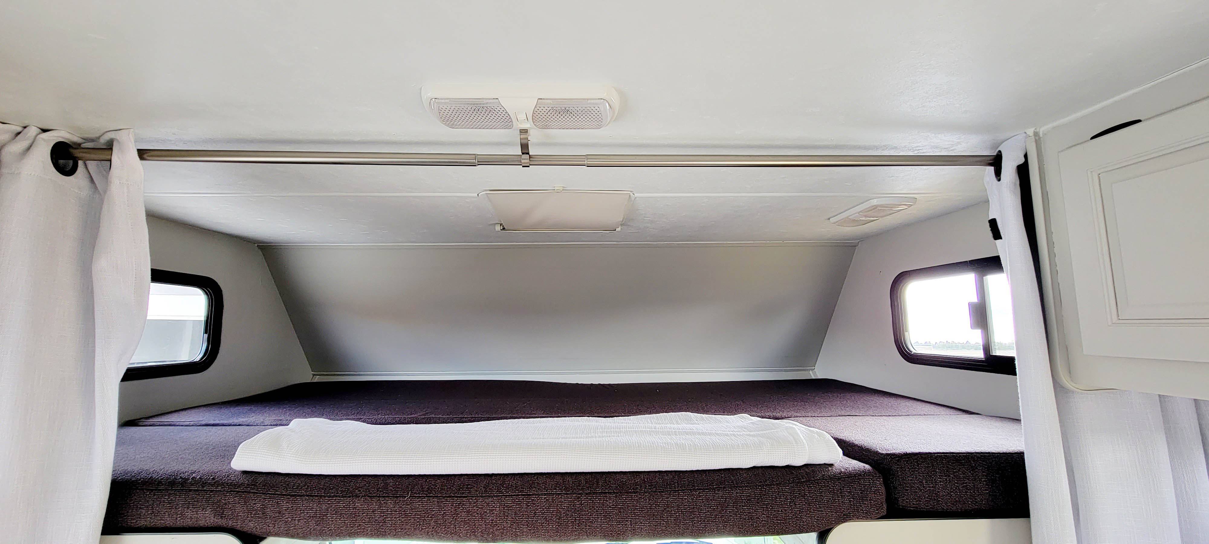 Inside an RV rental: a spacious overhead bunk sleeping area with windows & privacy curtains.. Thor Majestic 2018