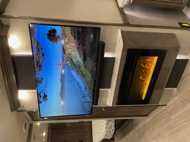 Modern RV rental interior featuring a large TV with a scenic view, soundbar, and an inviting electric fireplace.. Fleetwood Frontier 2022