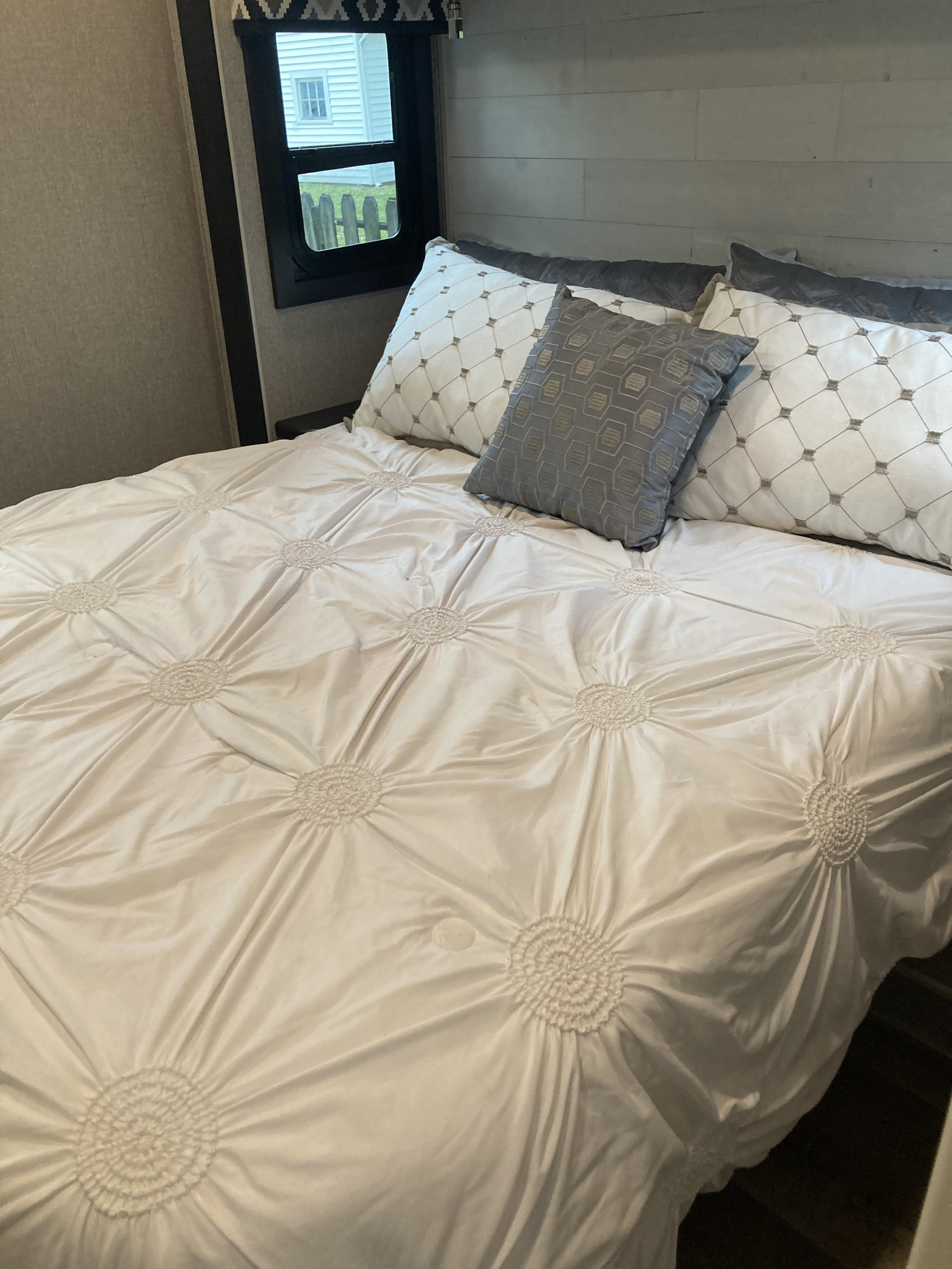 RV rental interior: Inviting bedroom with a ruched comforter, patterned pillows, and a window view.. Jayco Greyhawk 2021