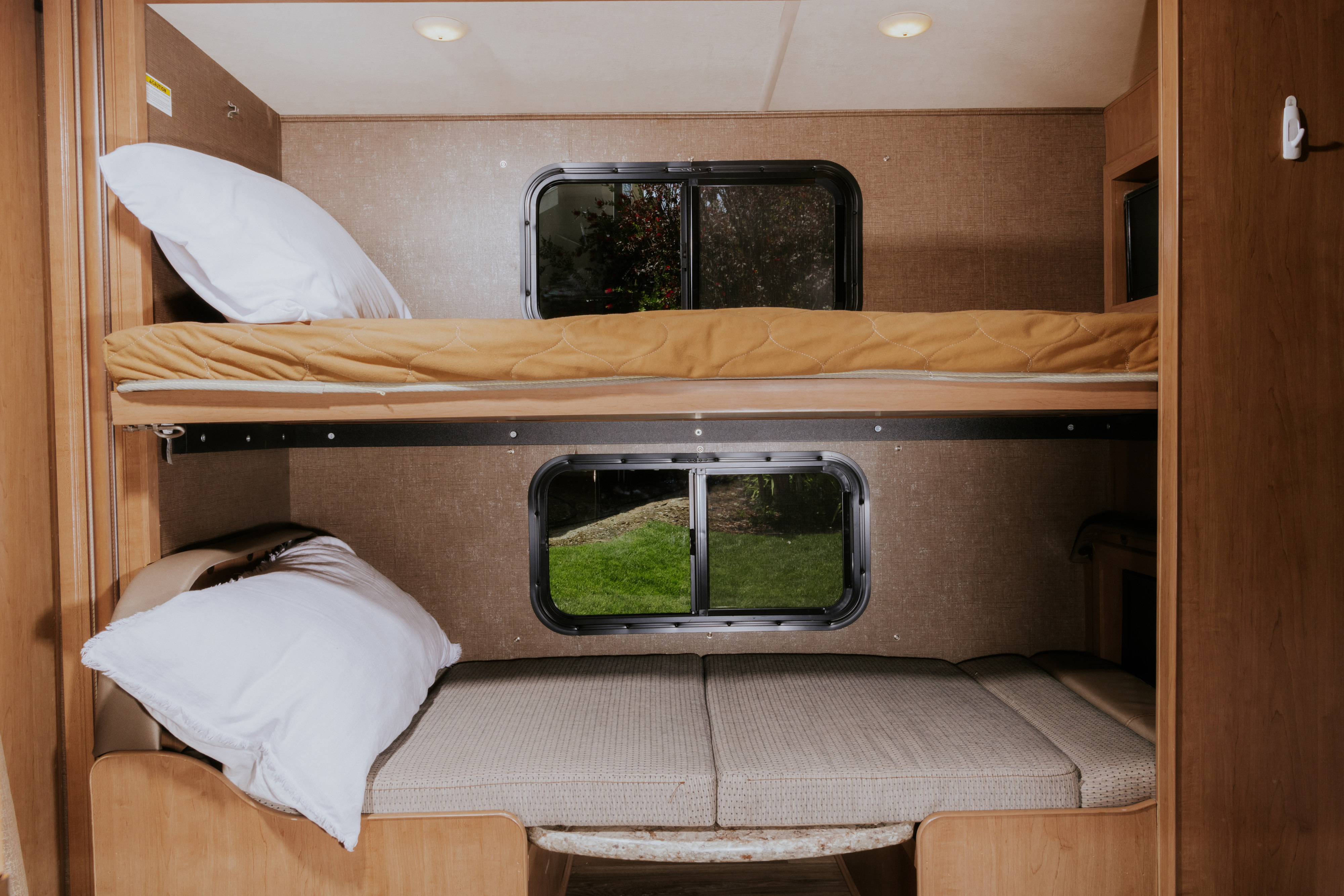 RV rental: Inside a recreational vehicle, two cozy bunk beds with windows showing outdoor views provide sleeping space.. Thor Four Winds 2019
