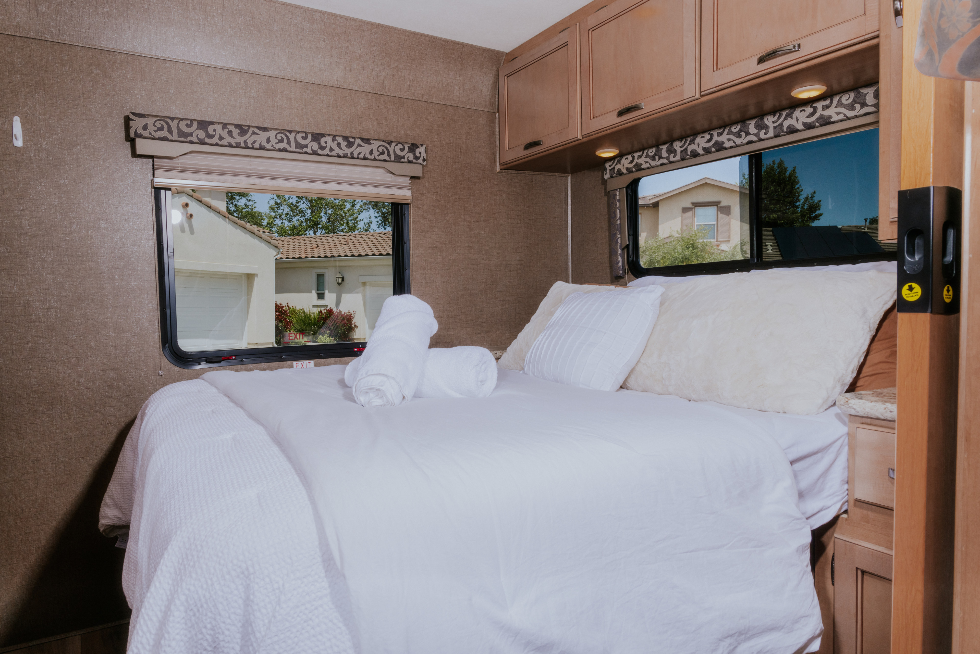 Relaxing RV rental bedroom with a fresh white bed, soft pillows, and convenient overhead storage. Ideal for comfortable travel.. Thor Four Winds 2019