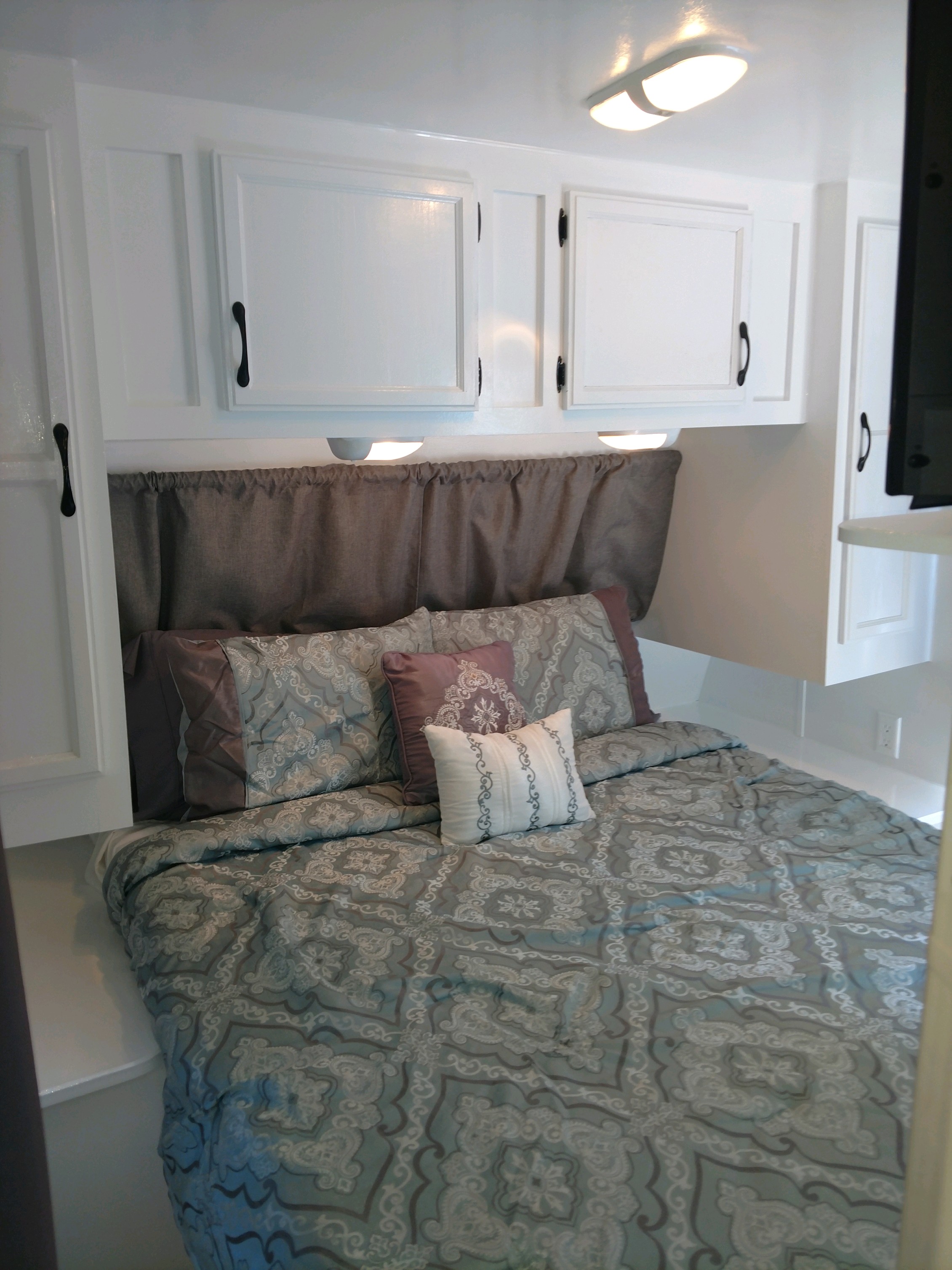 Cozy RV rental bedroom with white overhead cabinets, task lighting, and inviting blue patterned bedding. Perfect for your travels.. Jayco Jay Flight 2006