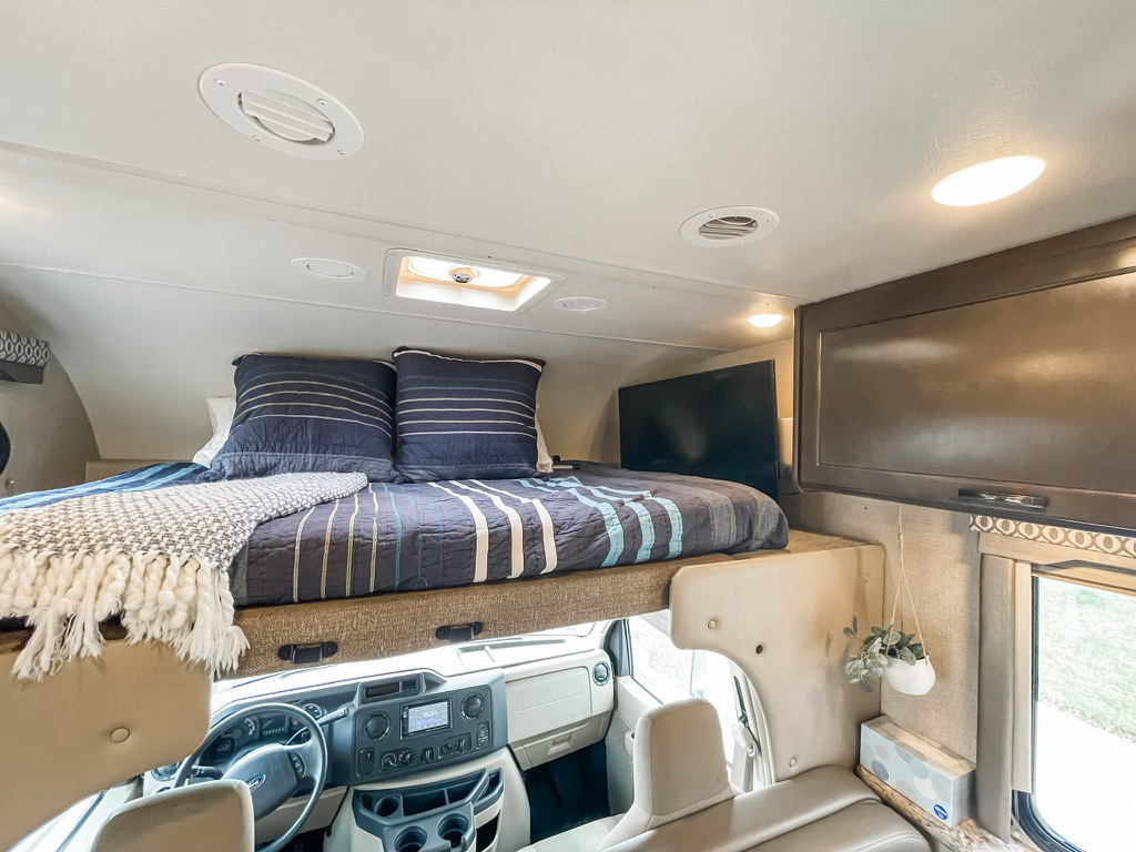 Cozy RV rental interior shows a cab-over bed, TV, and cockpit. Ready for comfortable road trips.. Thor Freedom Elite 2017