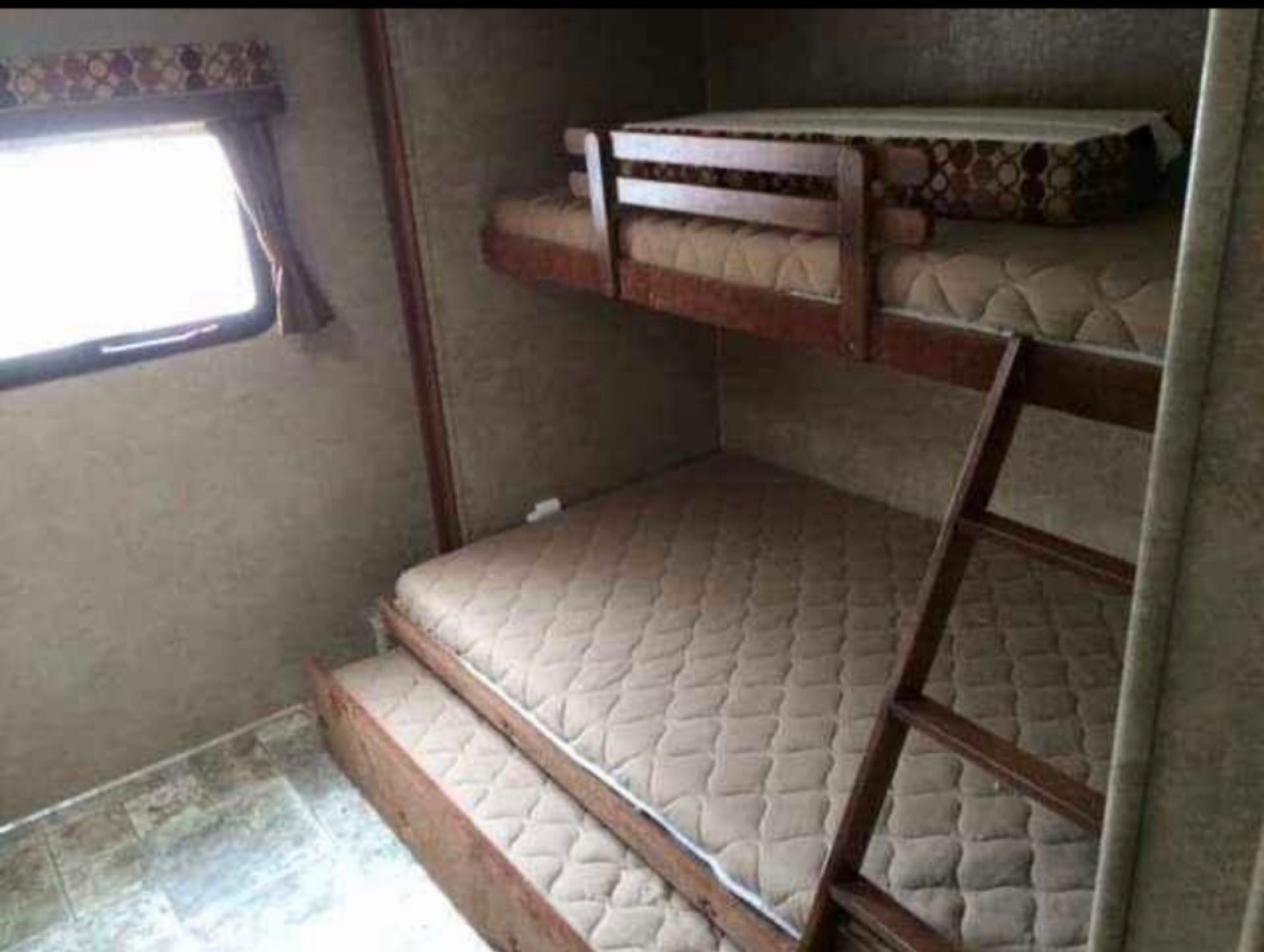 RV rental bunk beds: wooden frames, patterned top mattress, and a bright window. Ideal compact accommodation for travel.. Spree Spree Trailer 2014