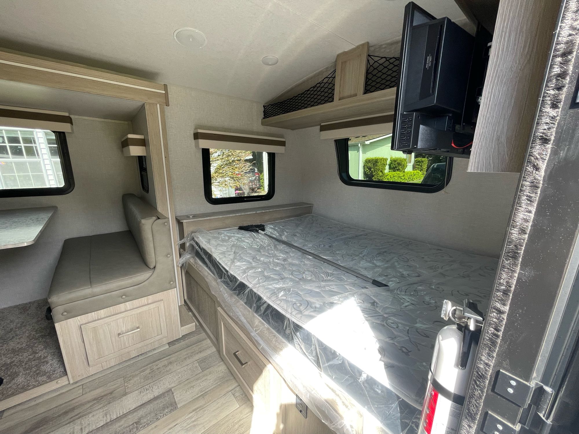 Interior of a modern rv rental showing a bed, dining booth, wall-mounted TV, and fire extinguisher.. Forest River Other 2022
