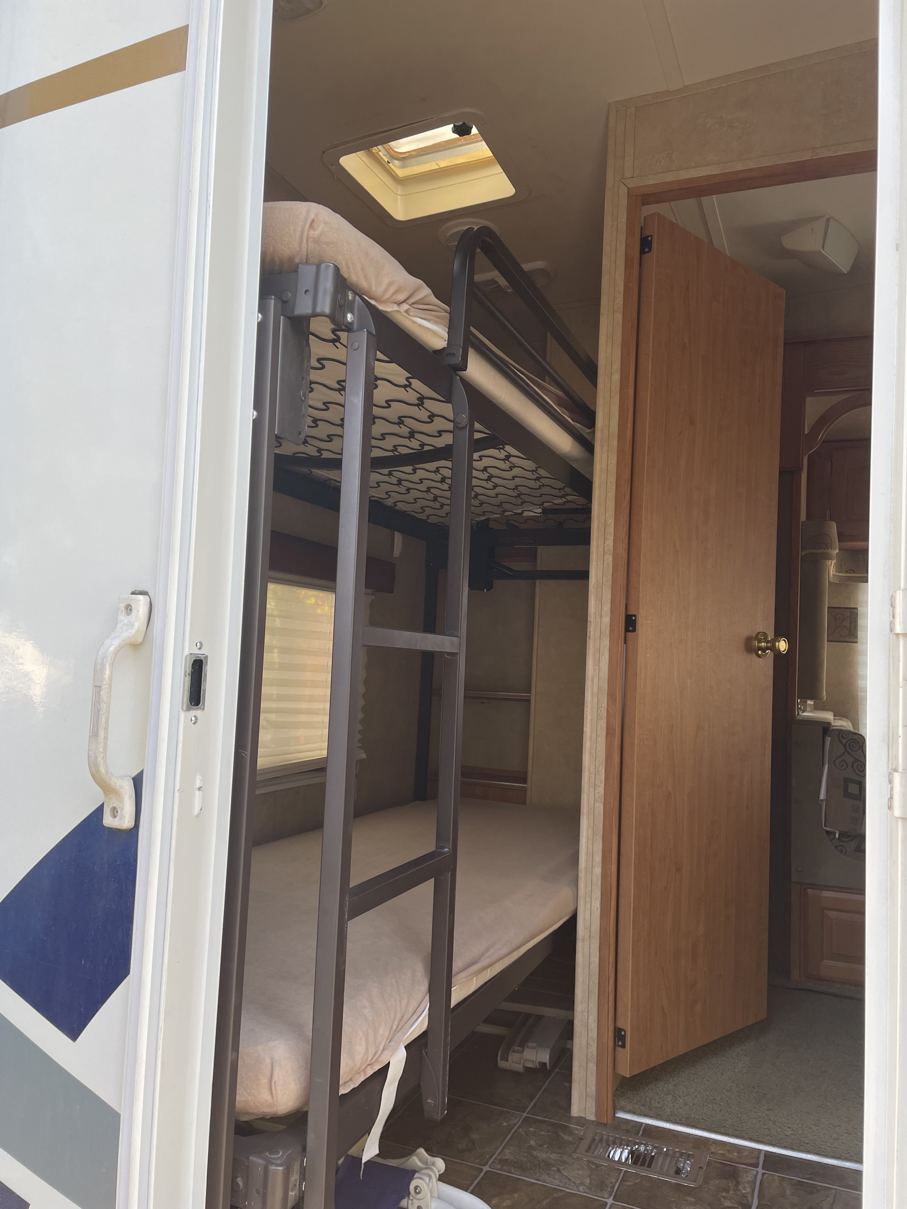 Explore this RV rental's interior featuring convenient bunk beds and an open door to more living space. Ideal for family trips.. Forest River Wildcat 2008