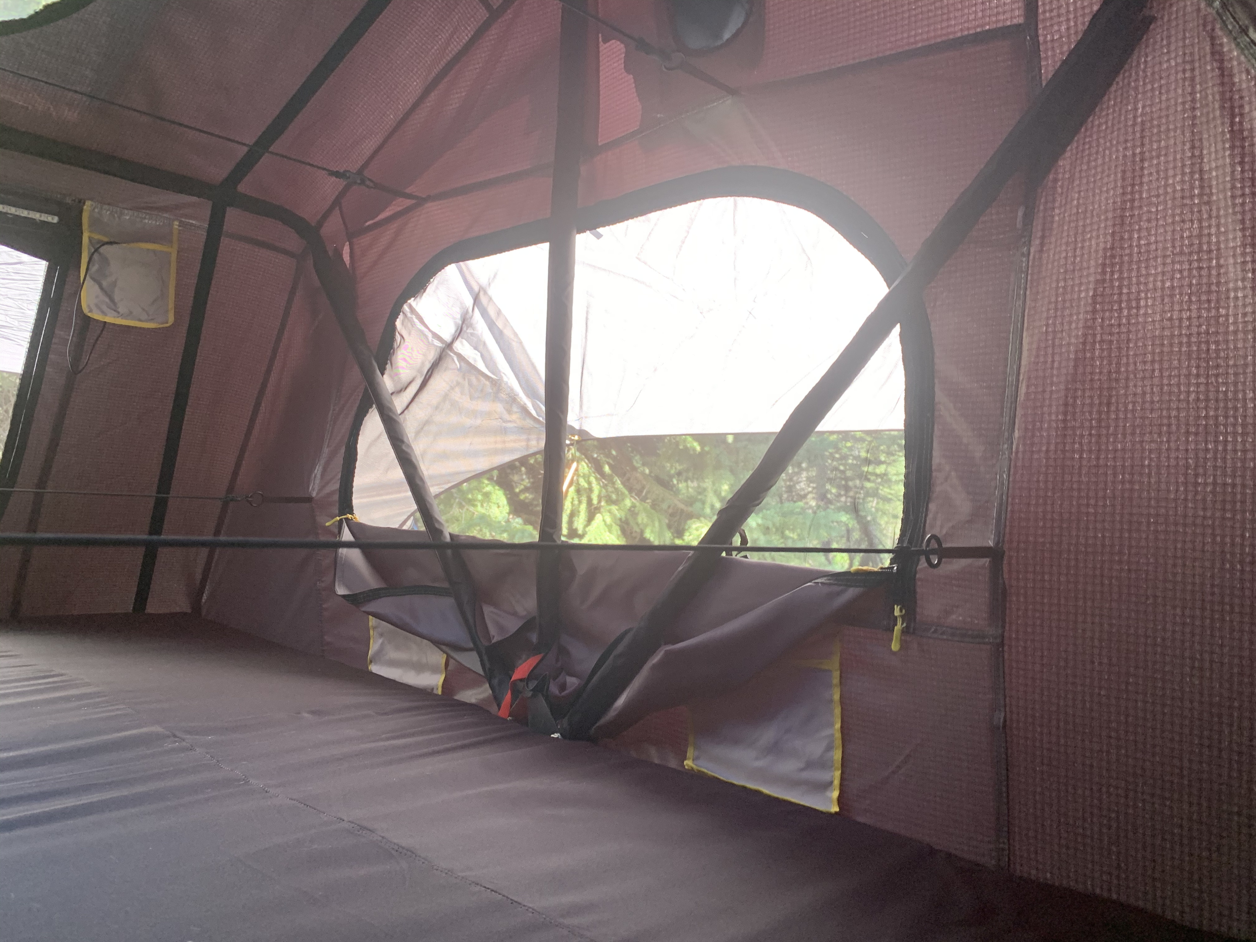 Cozy rooftop tent interior with a plush sleeping pad & scenic tree view. Ideal for an RV rental camping trip.. Smittybilt Overlander XL Gen 2 RTT 2021