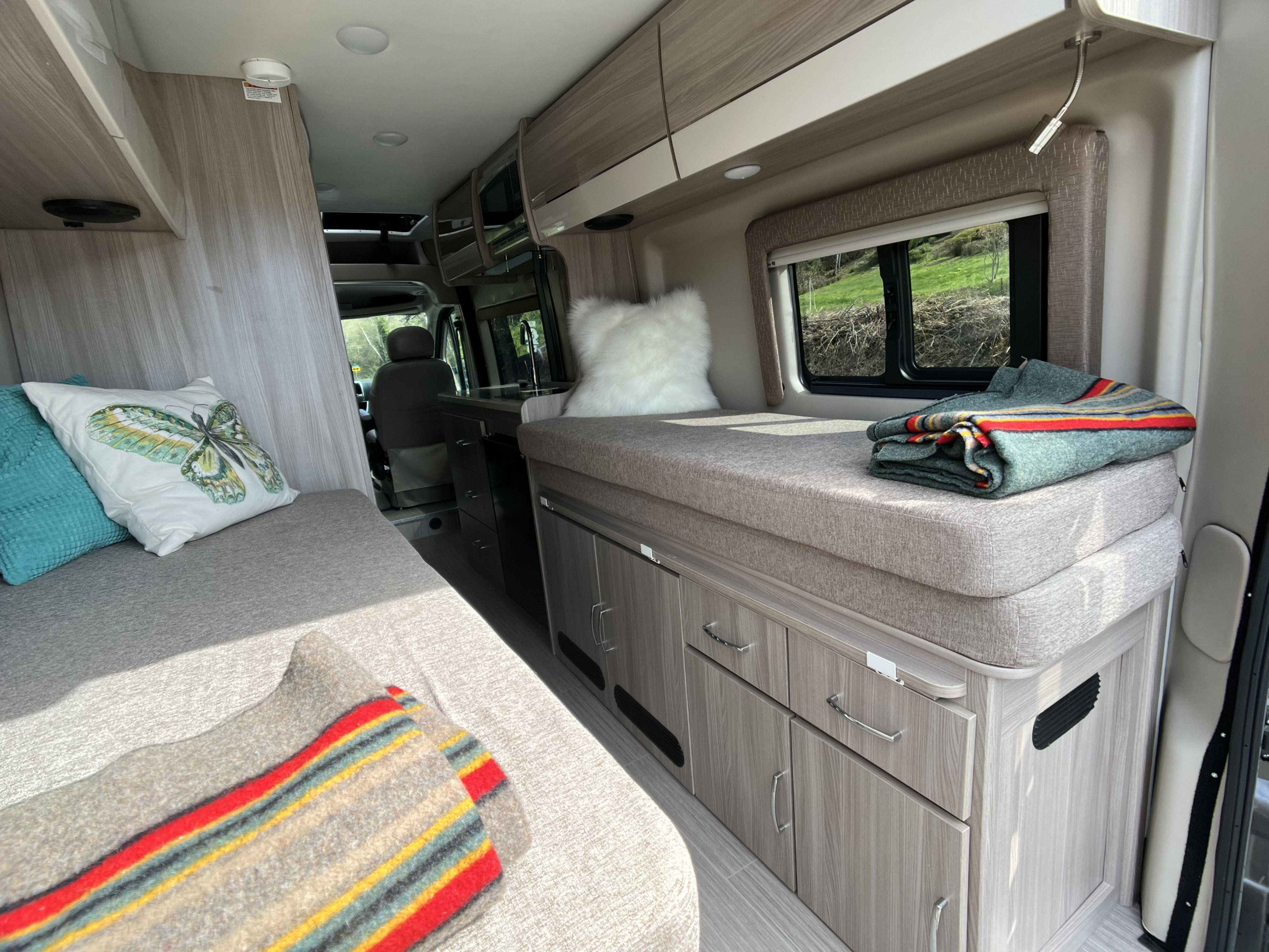Spacious RV rental interior featuring comfortable seating/sleeping areas, a compact kitchen, and ample storage for travel.. Dodge Ram Thor Thor 2022