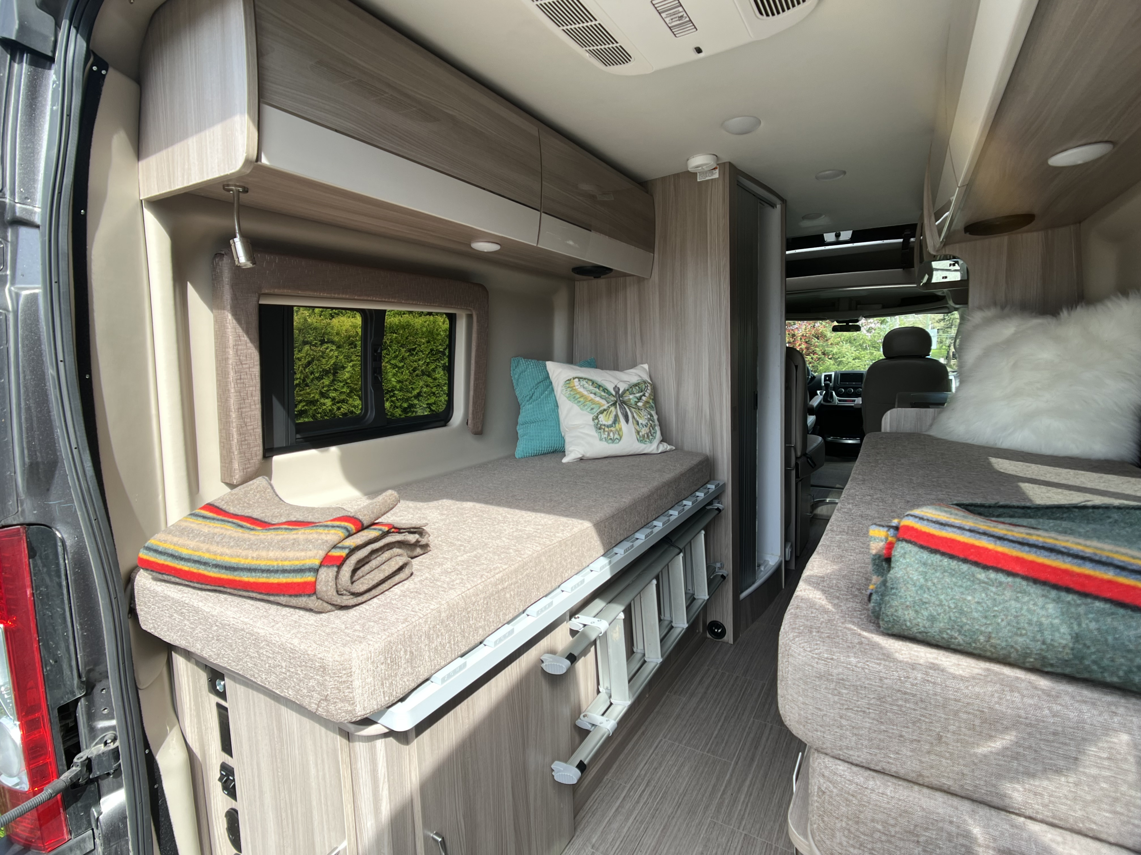 Compact RV rental interior featuring cozy beds, overhead storage, and a scenic window view, ideal for travel.. Dodge Ram Thor Thor 2022
