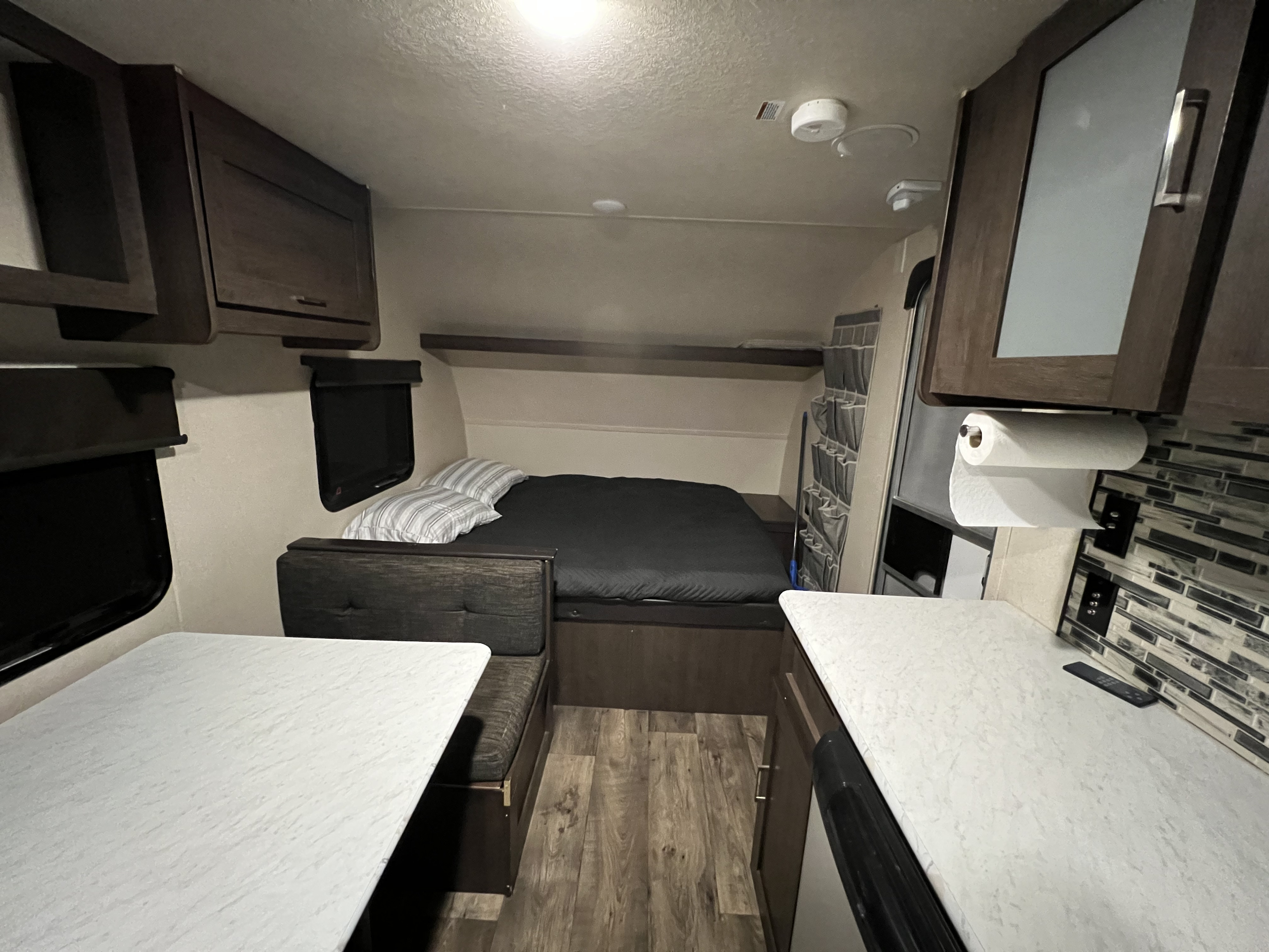 Cozy RV rental interior: a comfy bed, dinette seating, and kitchenette with dark cabinets and light counters, ready for travel.. Forest River Wildwood FSX 2018