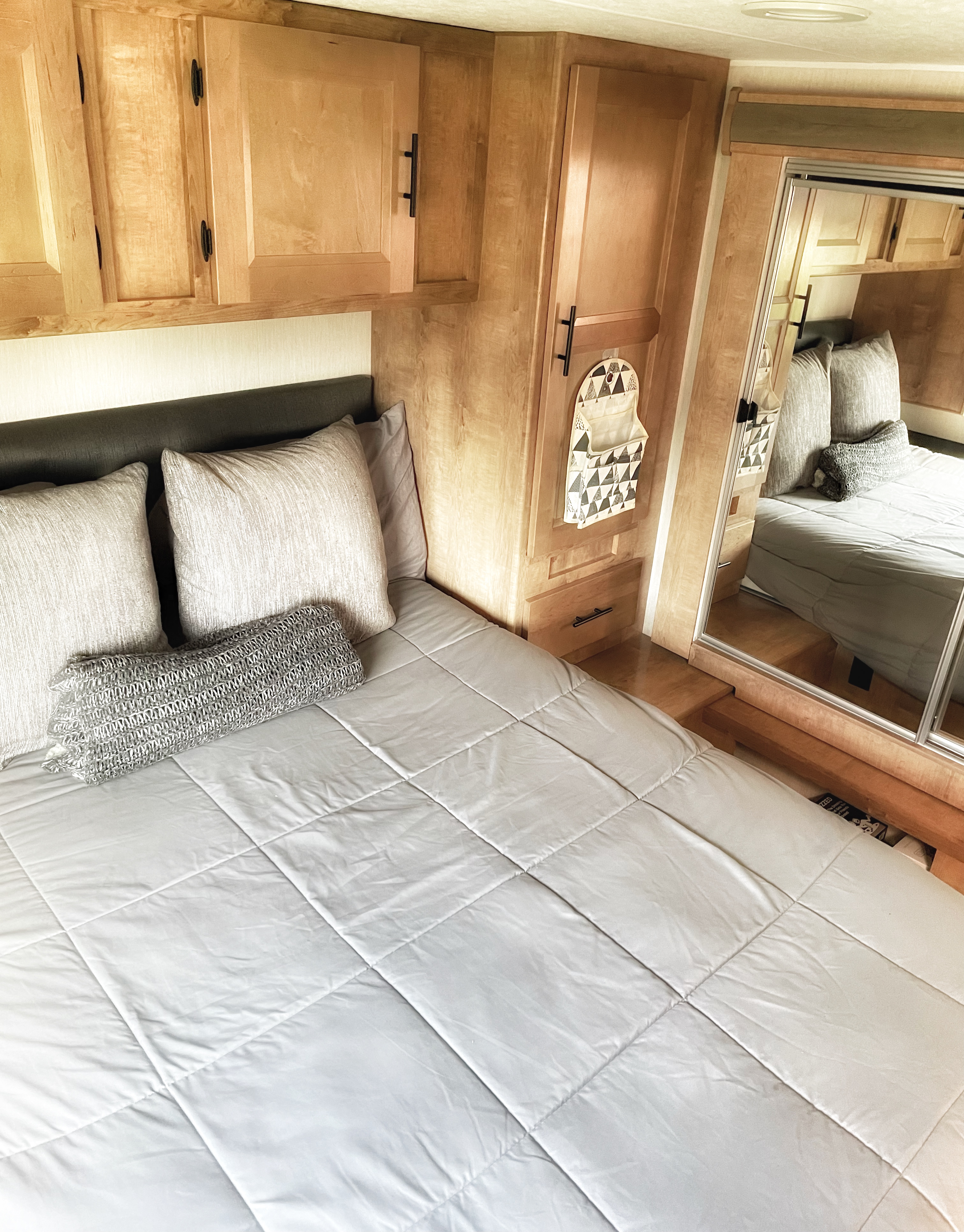 Cozy RV rental bedroom with comfortable bed, built-in wood storage, and full-length mirror. Perfect for your travels.. Other Other 2021