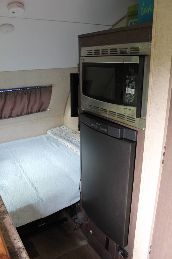 Compact RV rental interior featuring a cozy bed, microwave, and refrigerator, perfect for travel comfort.. R-Pod Hood River Edition 2016