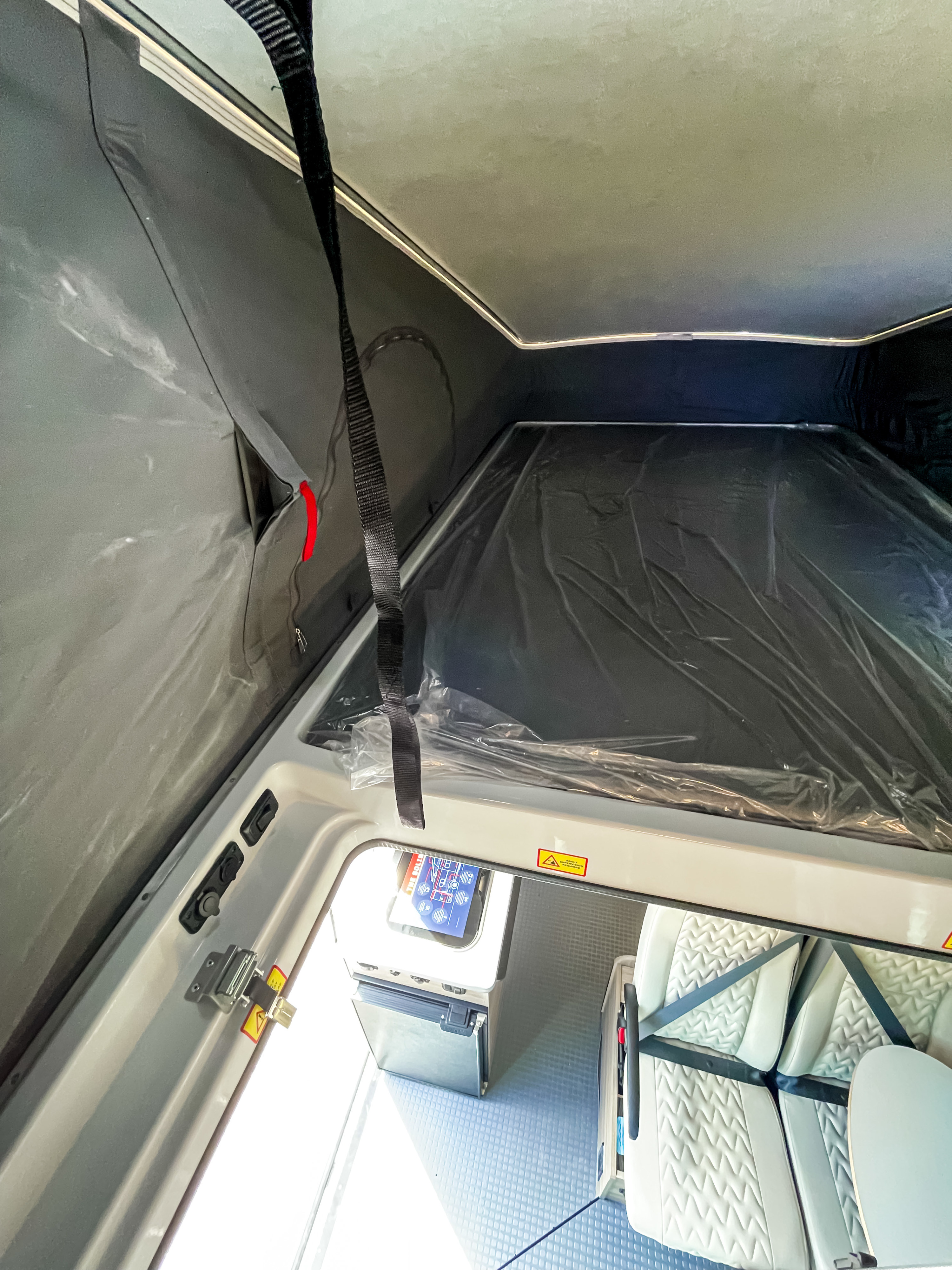 RV rental interior with a pop-top bed (still wrapped), dinette seating, and a compact kitchenette, ready for adventure.. Winnebago Solis 2022