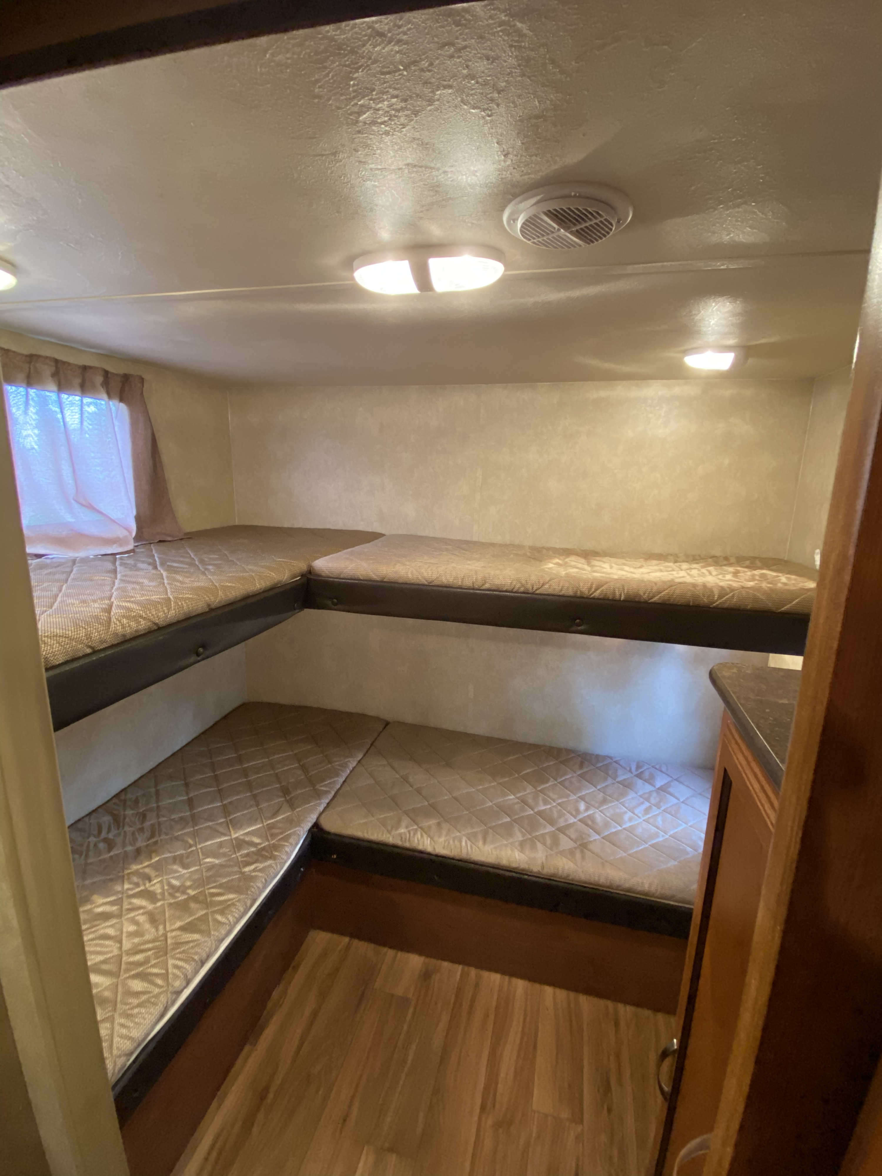 Comfortable RV rental bunk beds with quilted mattresses create a cozy sleeping area. Features window, lights, and wood floor.. Forest River Wildwood X-Lite 2014