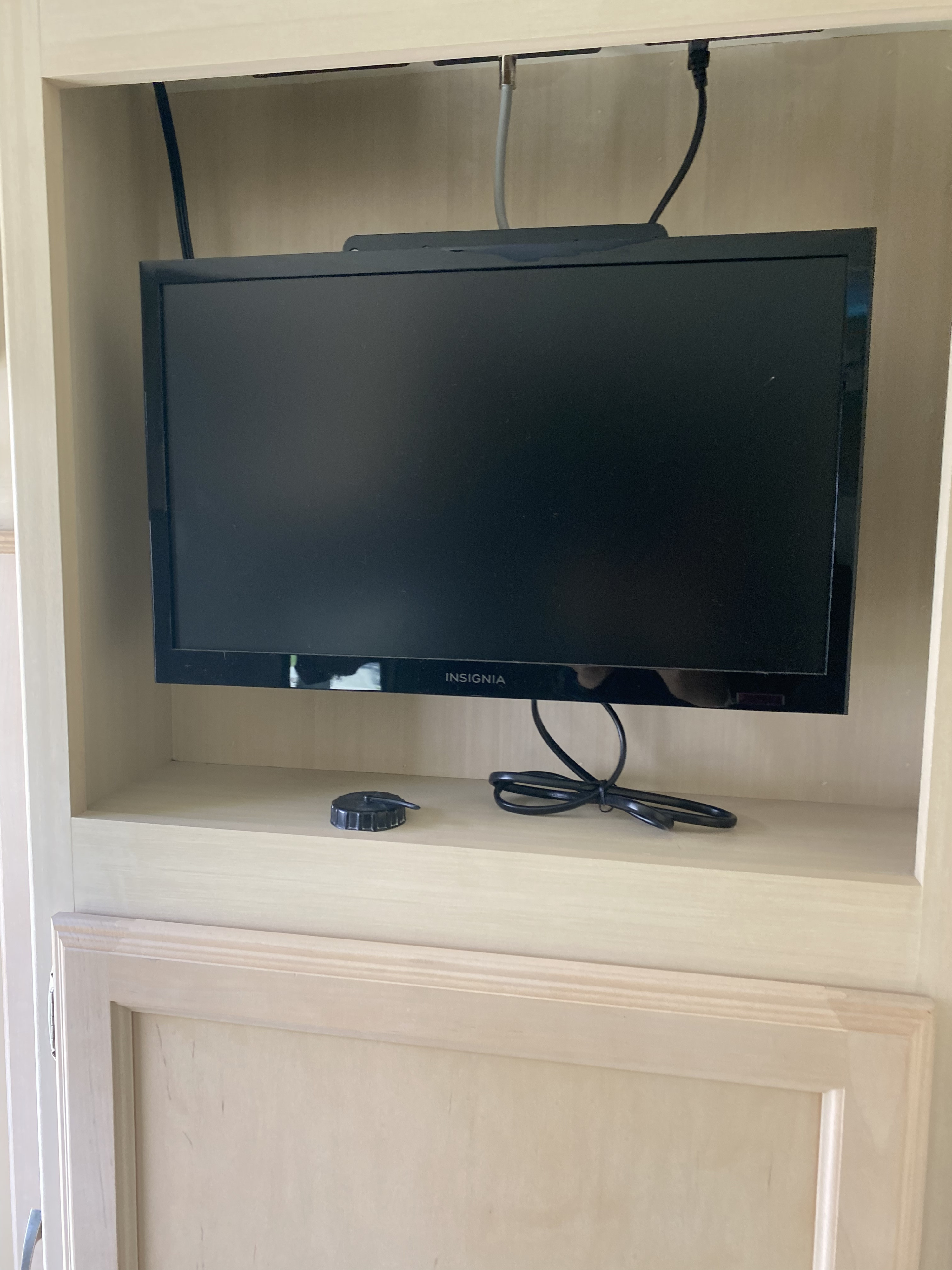 Insignia flat-screen TV mounted in an RV rental cabinet, showing cables and power cord for entertainment.. Winnebago Minnie Winnie 2017