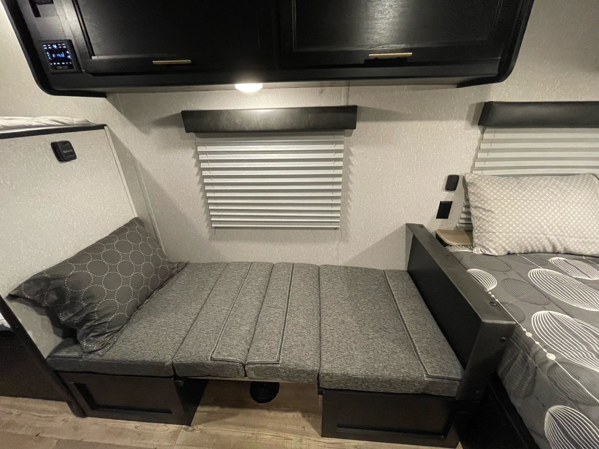 Cozy RV rental interior showing a flexible seating area that converts to a bed, a main bed, and overhead storage.. Forest River Cherokee Wolf Pup 2022