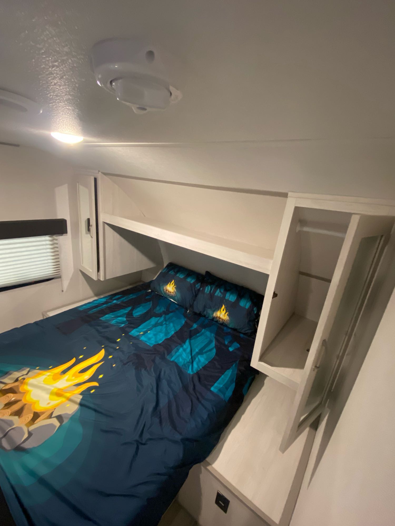 Inside an RV rental: a cozy bedroom with campfire bedding, built-in storage, and a window. Compact for comfortable travel.. Other Tracer 2022