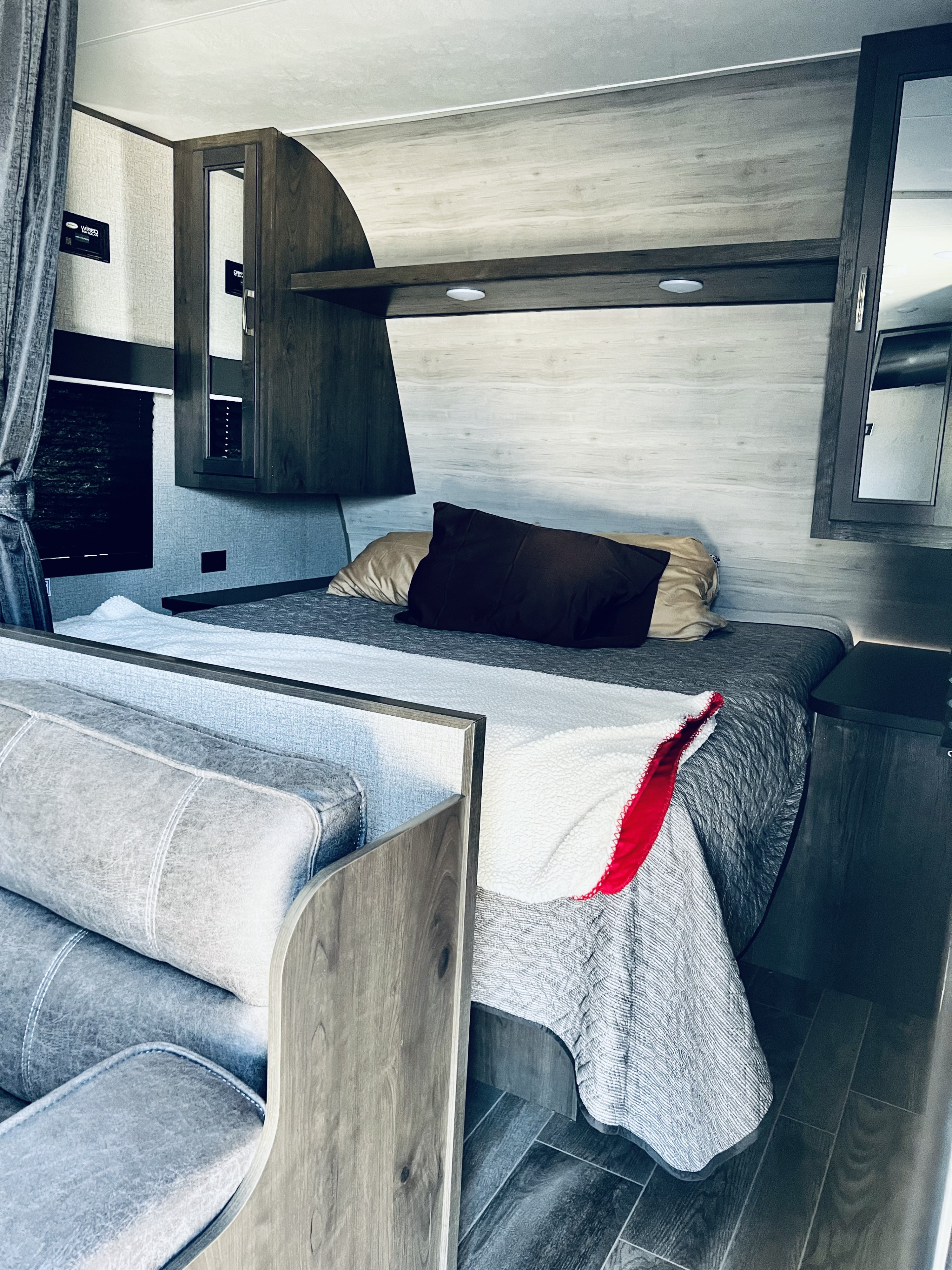 Modern rv rental interior: a clean bedroom with light wood walls, dark cabinets, and a comfortable bed with a white blanket.. Jayco Jay Flight SLX Rocky Mountain Edition 2021