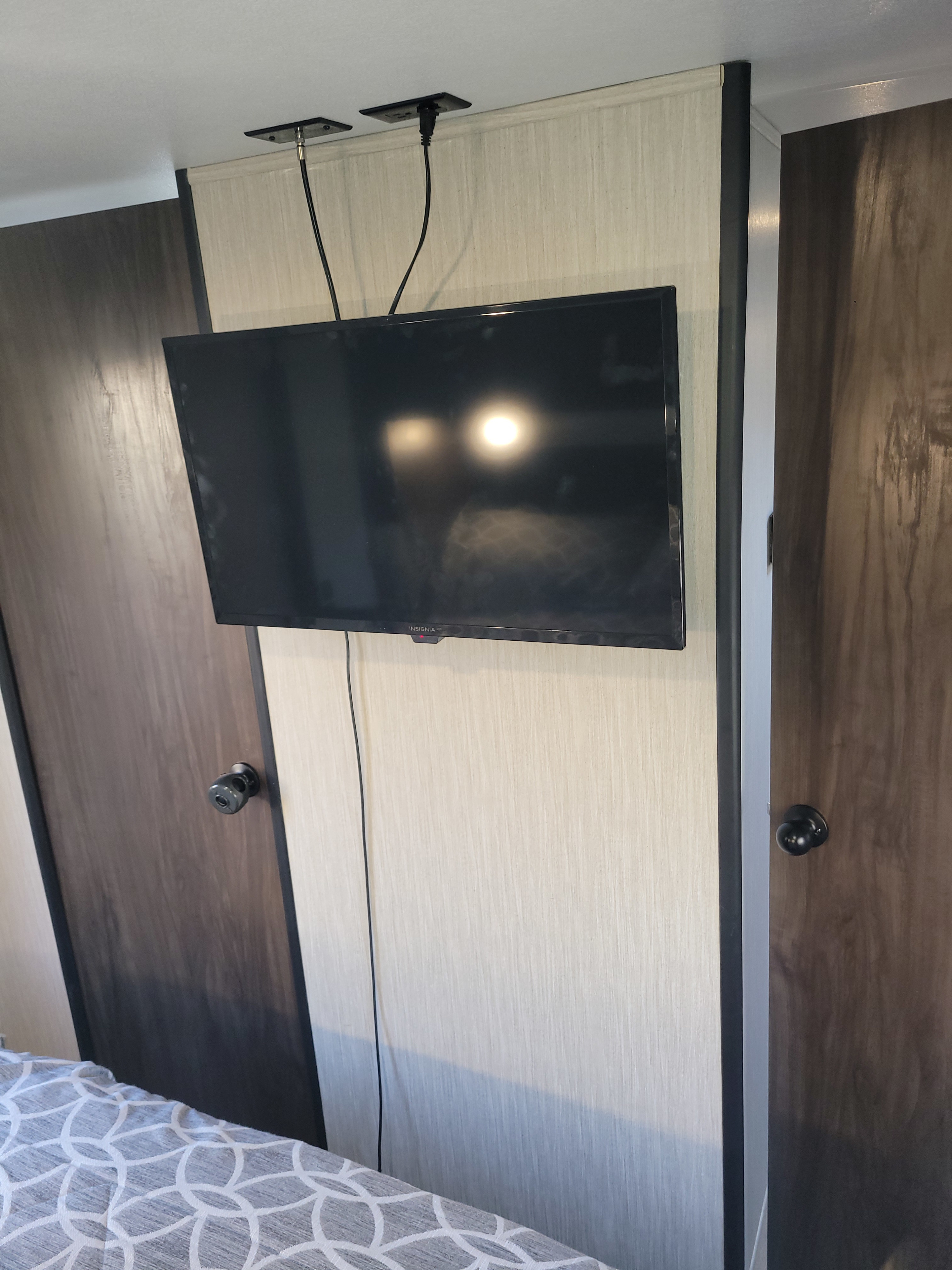 Compact rv rental interior featuring a wall-mounted TV, visible cables, and dark wood doors, suggesting a cozy sleeping area.. Forest River Cherokee Grey Wolf 2021