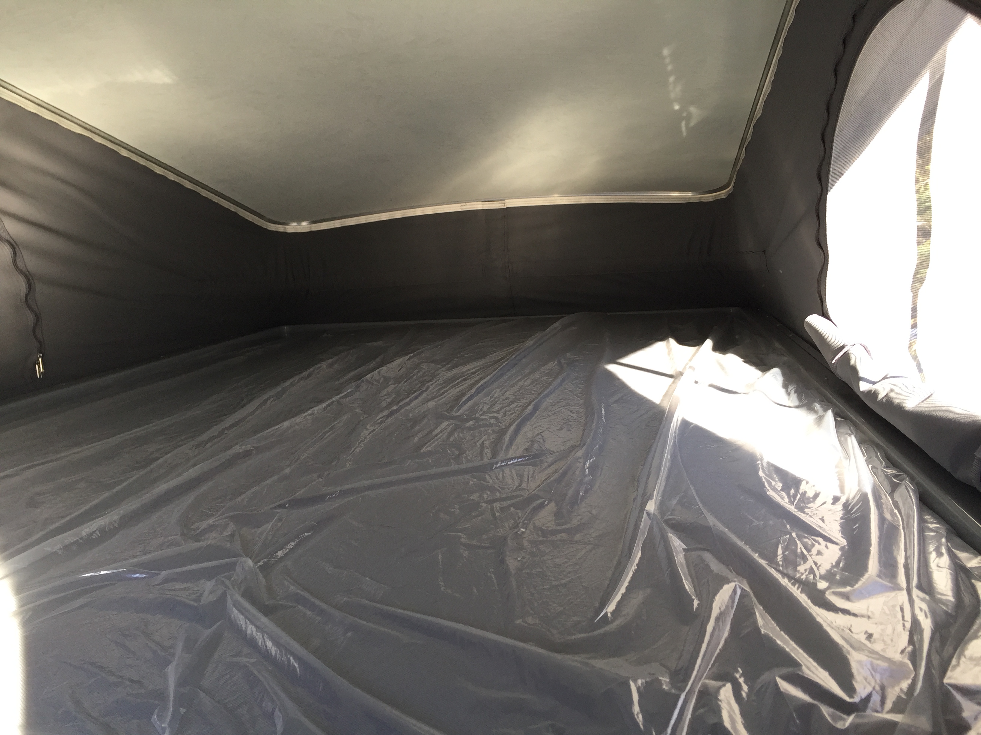 RV rental: Inside a pop-top camper featuring a light ceiling, dark fabric walls, and a crinkled plastic-covered floor.. Winnebago Solis 2022