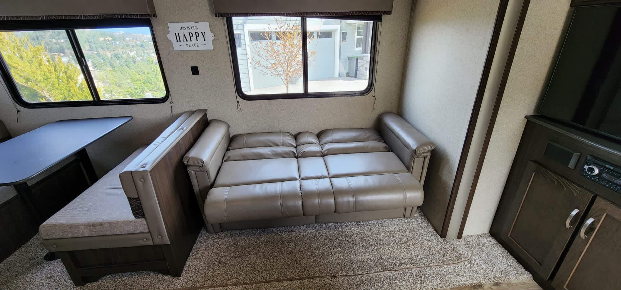 Cozy RV rental interior with a dinette, comfortable convertible sofa bed, and entertainment center.. Keystone RV Springdale 2020