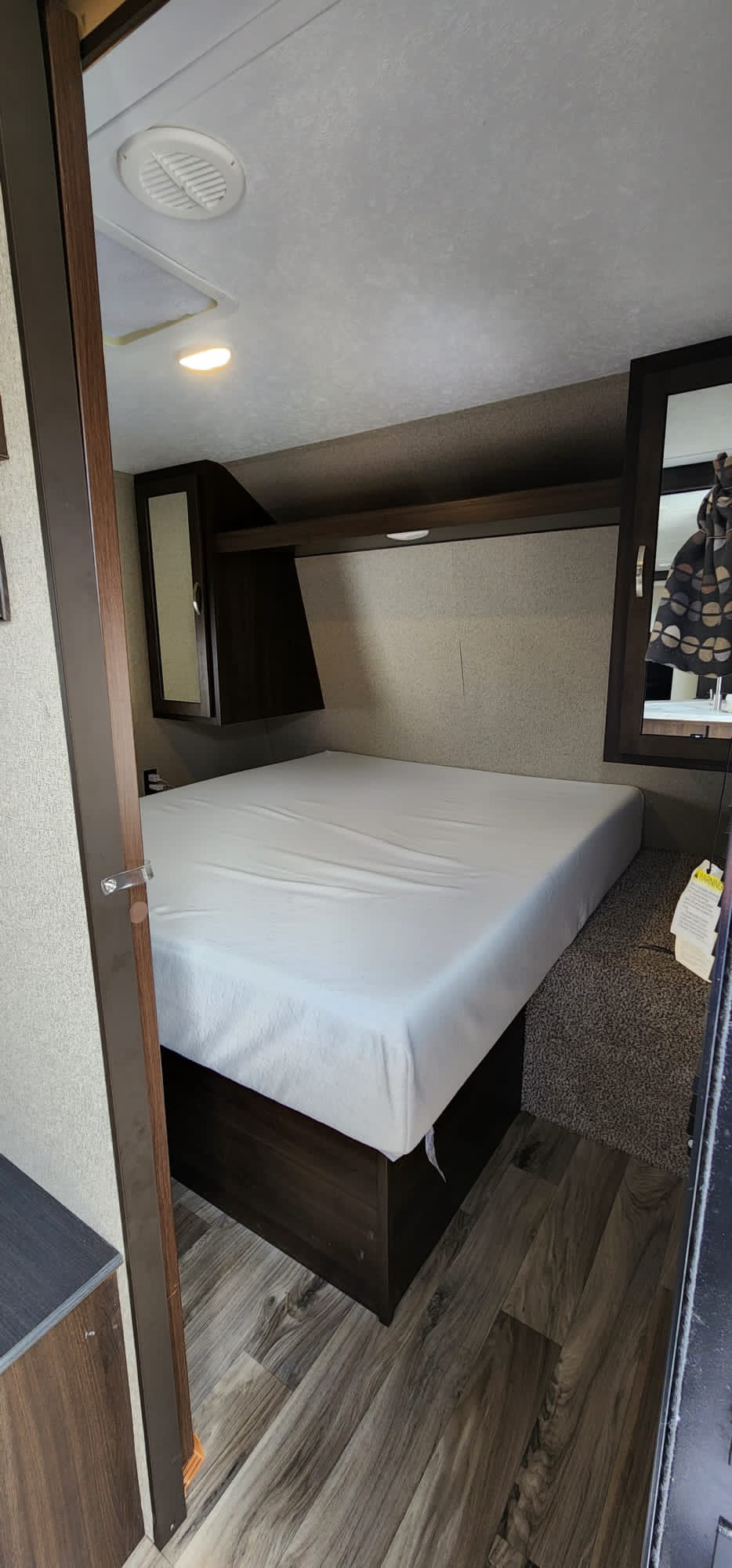 Experience comfort in this RV rental bedroom: a large bed, mirrored cabinets, overhead storage, and ceiling vent.. Keystone RV Springdale 2020