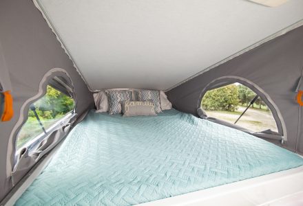 A pop-up RV rental bed with a blue comforter offers scenic views for a comfortable night.. Roadtrek Roadtrek Class B 2021