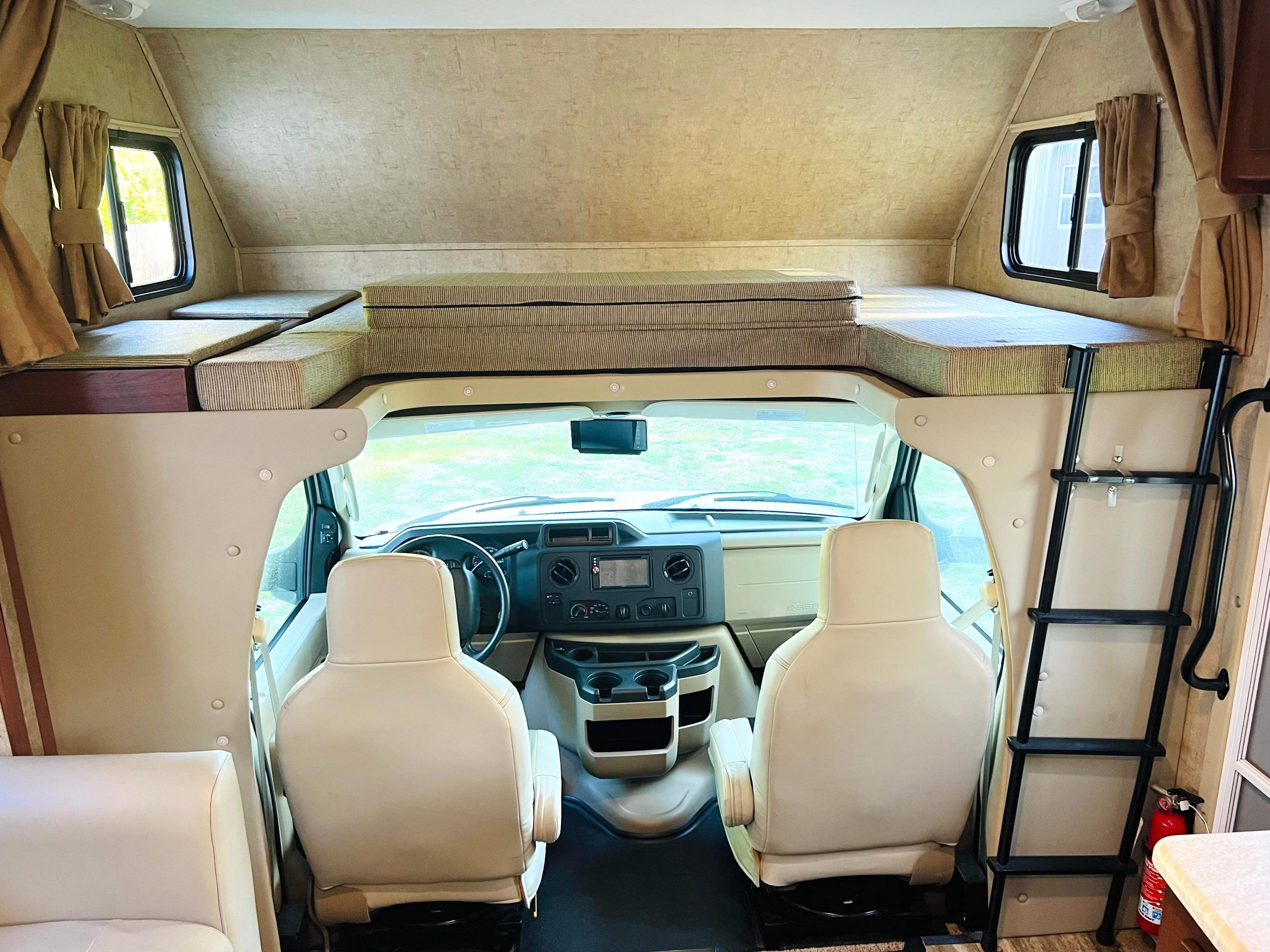Inside a clean RV rental, featuring the driver's cockpit area and the large cab-over bed bunk with ladder.. Forest River Other 2016