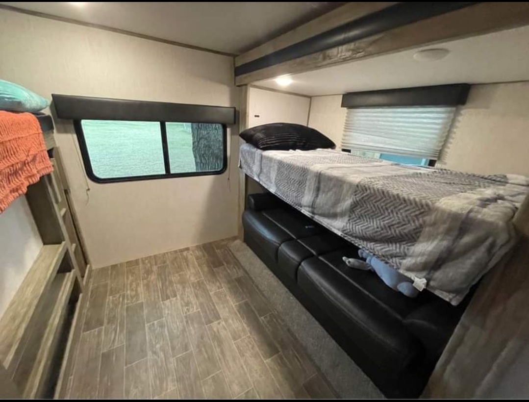 RV rental interior: cozy bunk beds, a seating area, and modern flooring. Perfect for family travel trailer adventures.. Forest River Cherokee Alpha Wolf 2021