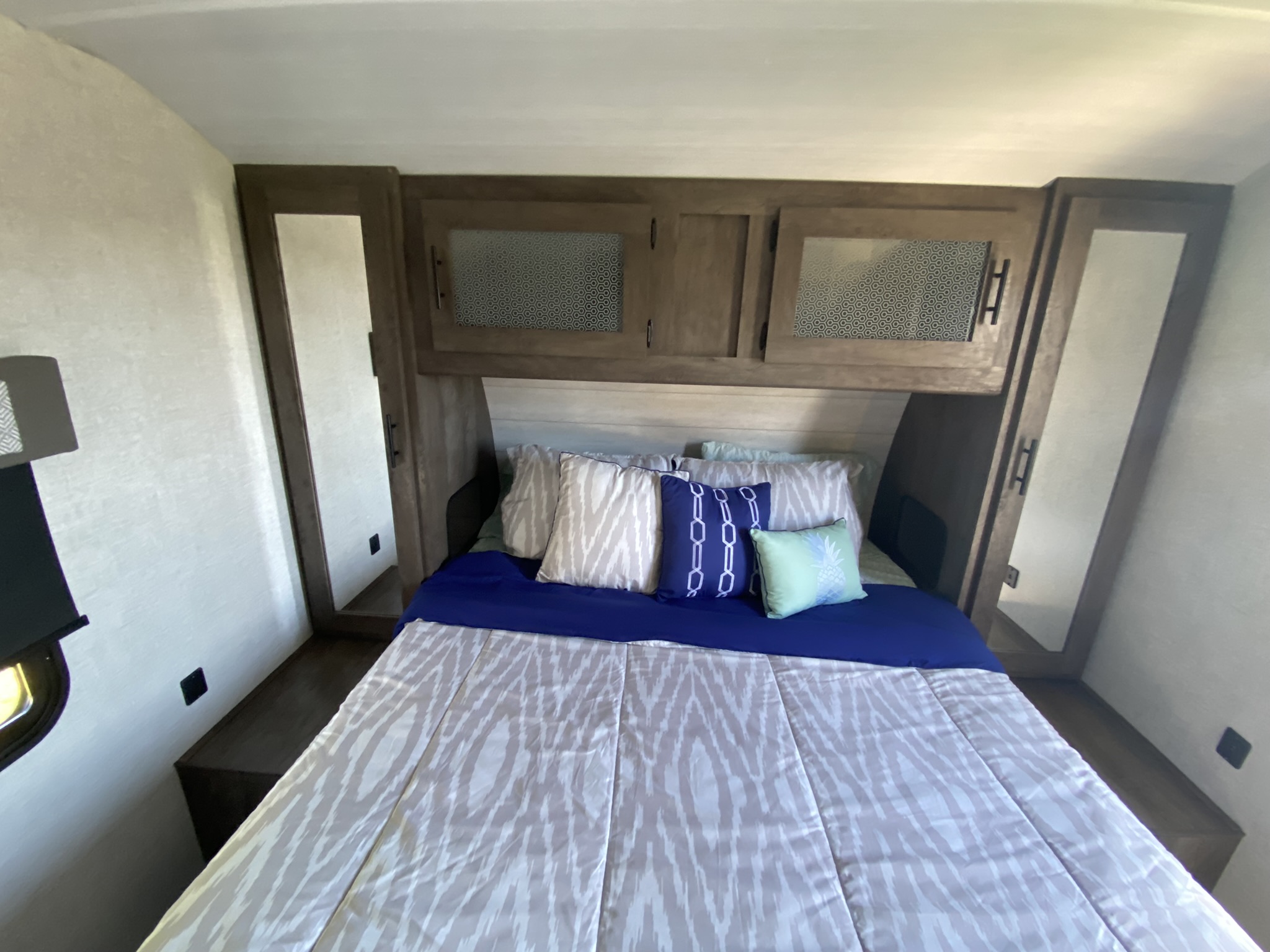 RV rental bedroom showcasing a bed with blue bedding, patterned pillows, and built-in wooden cabinets including mirrored wardrobes.. Forest River Salem 2021