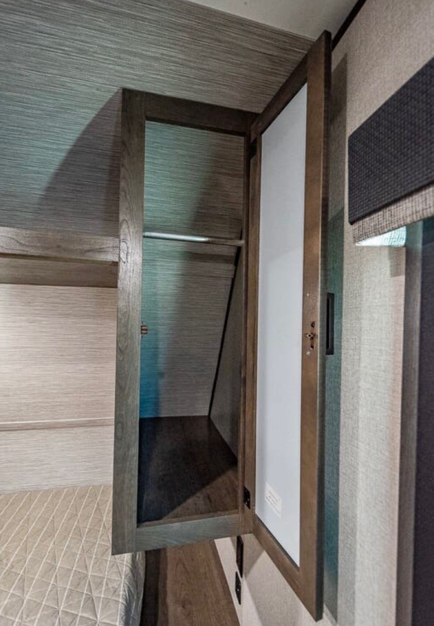 RV rental: Bedroom features an open wardrobe with hanging rod, wood trim, and a quilted bed for comfort.. Highland Ridge Olympia 26BHS 2022