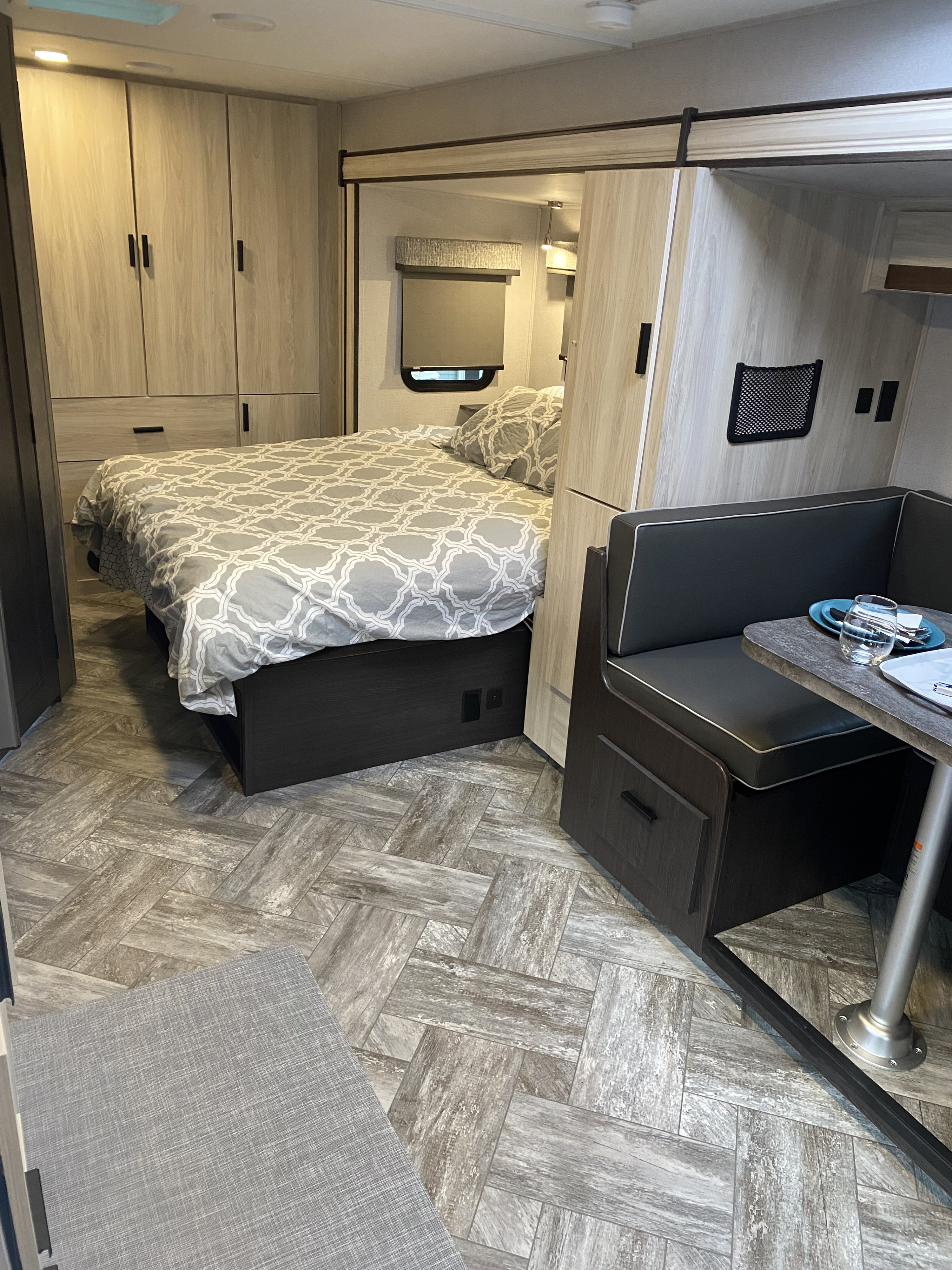 Modern RV rental interior showing a comfortable bedroom with storage and a compact dinette with table. Ideal for travel.. Other Other 2022