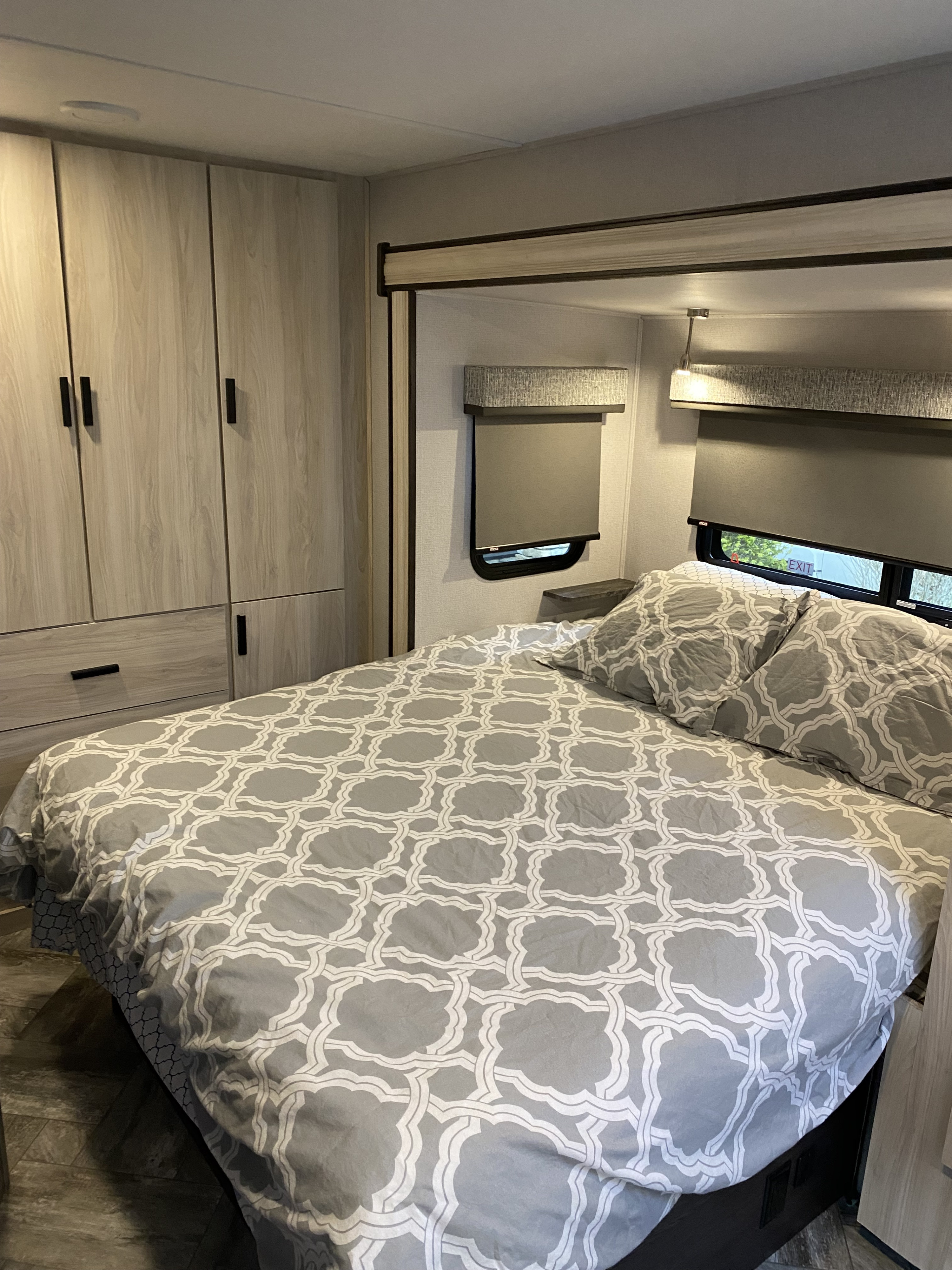 Comfortable RV rental bedroom with modern grey and white bedding, built-in cabinets, and practical window blinds.. Other Other 2022