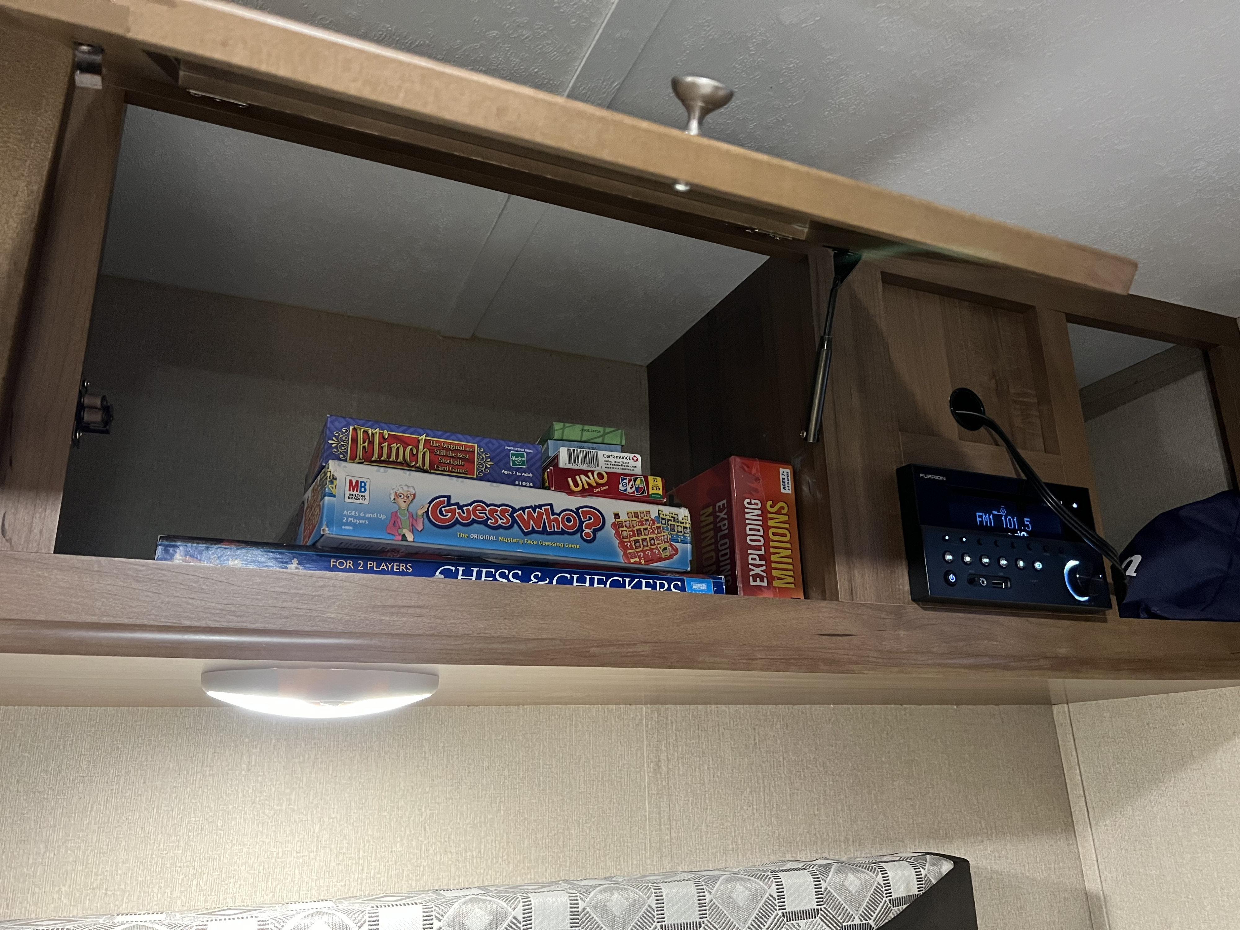 Overhead RV rental cabinet open, revealing board games, card games, and a Furrion entertainment system. Ready for fun!. Aspen Trail Aspen Trail Trailer 2018