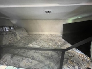 RV rental: Cozy over-cab bunk bed with patterned bedding and safety rail, ideal for compact travel accommodations.. Forest River Sunseeker 2018
