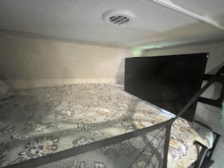 RV rental interior: A cozy bunk bed with patterned bedding and a TV, ideal sleeping area for travel.. Forest River Sunseeker 2018