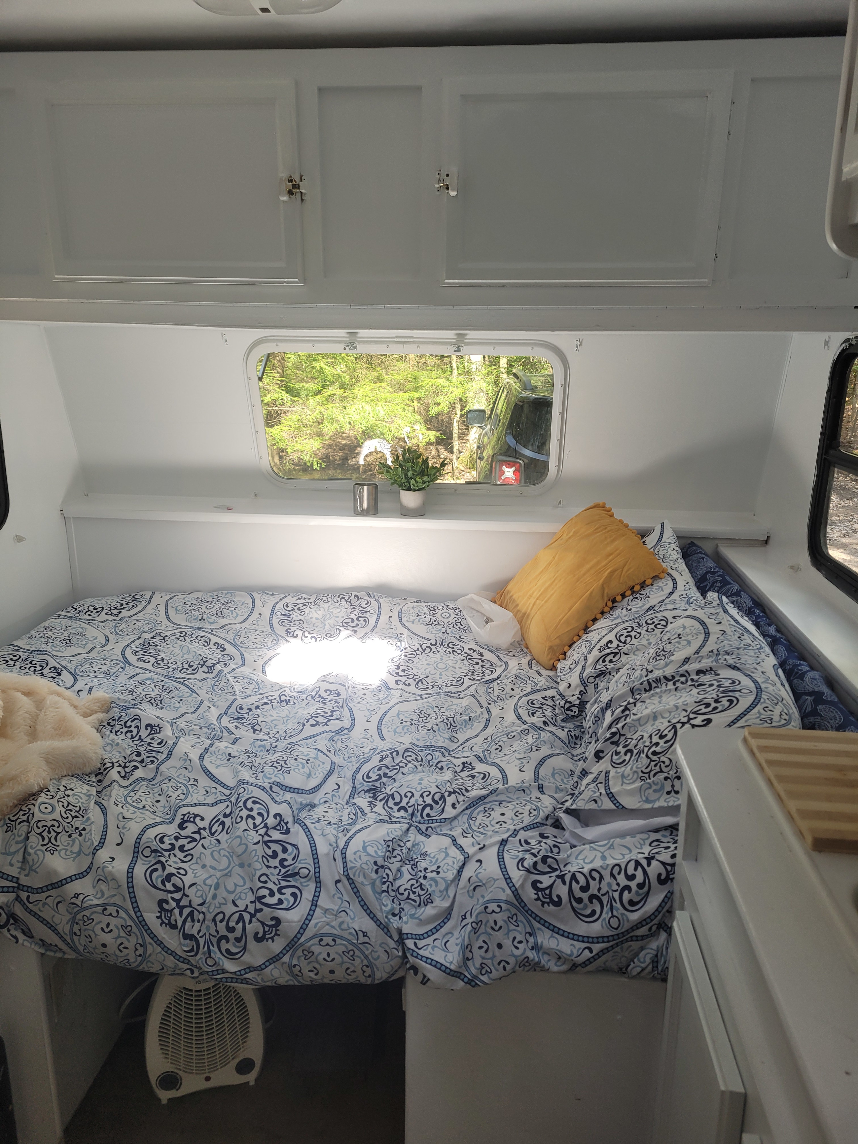 Cozy RV rental interior with patterned bed, yellow pillow, and window view of nature.. Starcraft Travel Star 2008