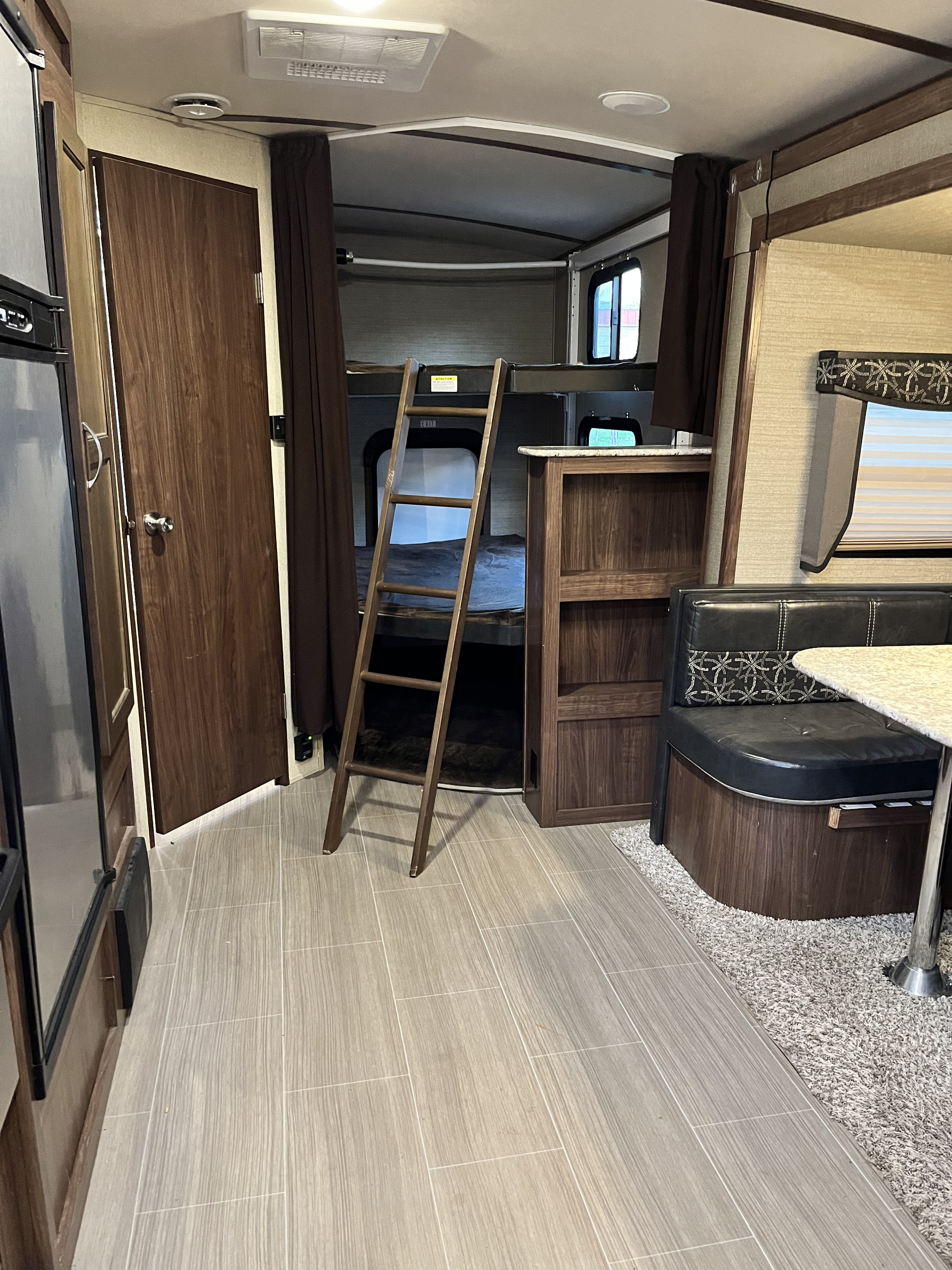 RV rental interior showcasing a cozy bunk bed area with ladder, dinette, and kitchen appliances. Ideal for families.. Dutchman Aerolite Luxury Class 2017