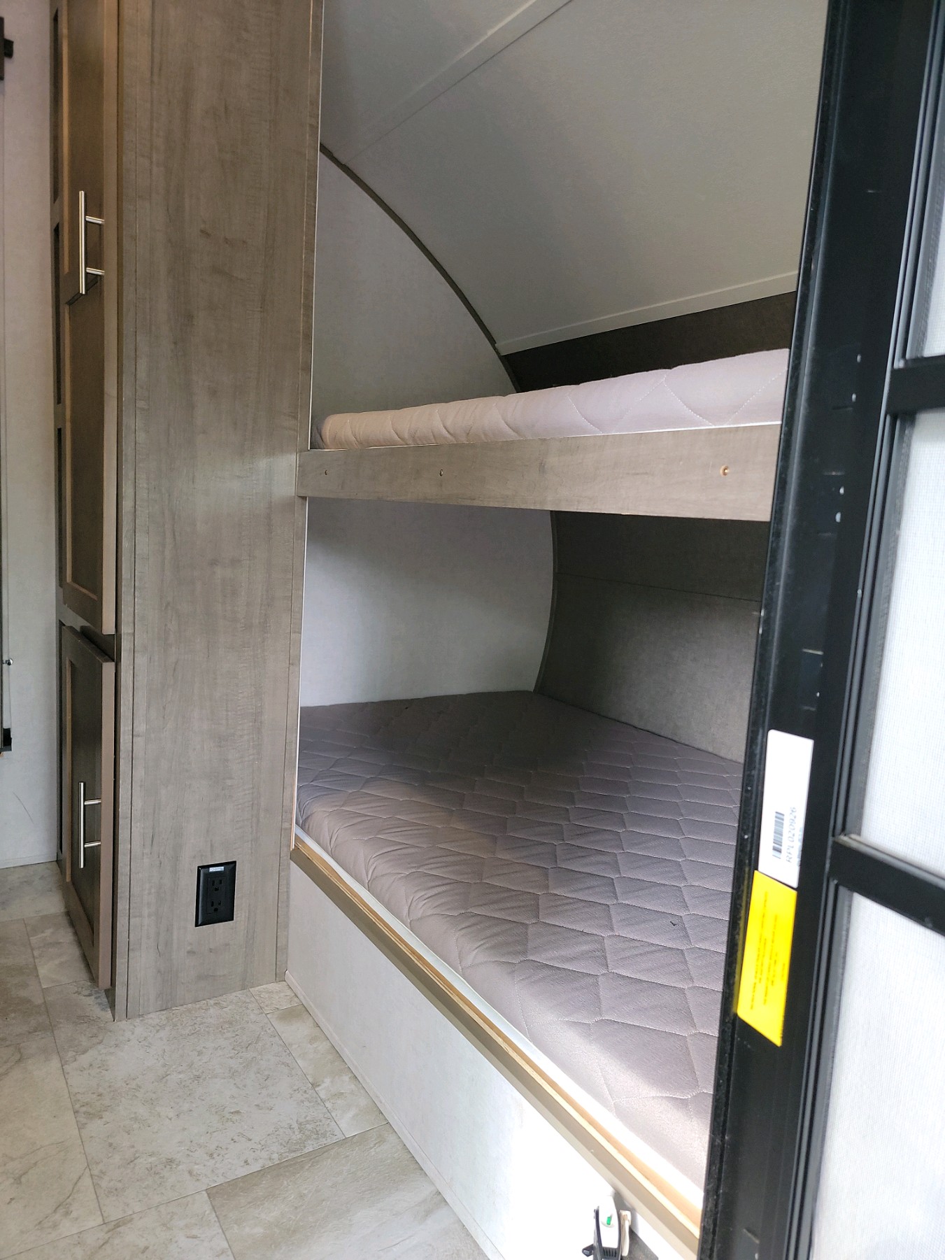 RV rental interior featuring comfortable bunk beds with quilted mattresses and a wood-toned storage cabinet.. Forest River RP-176T 2018