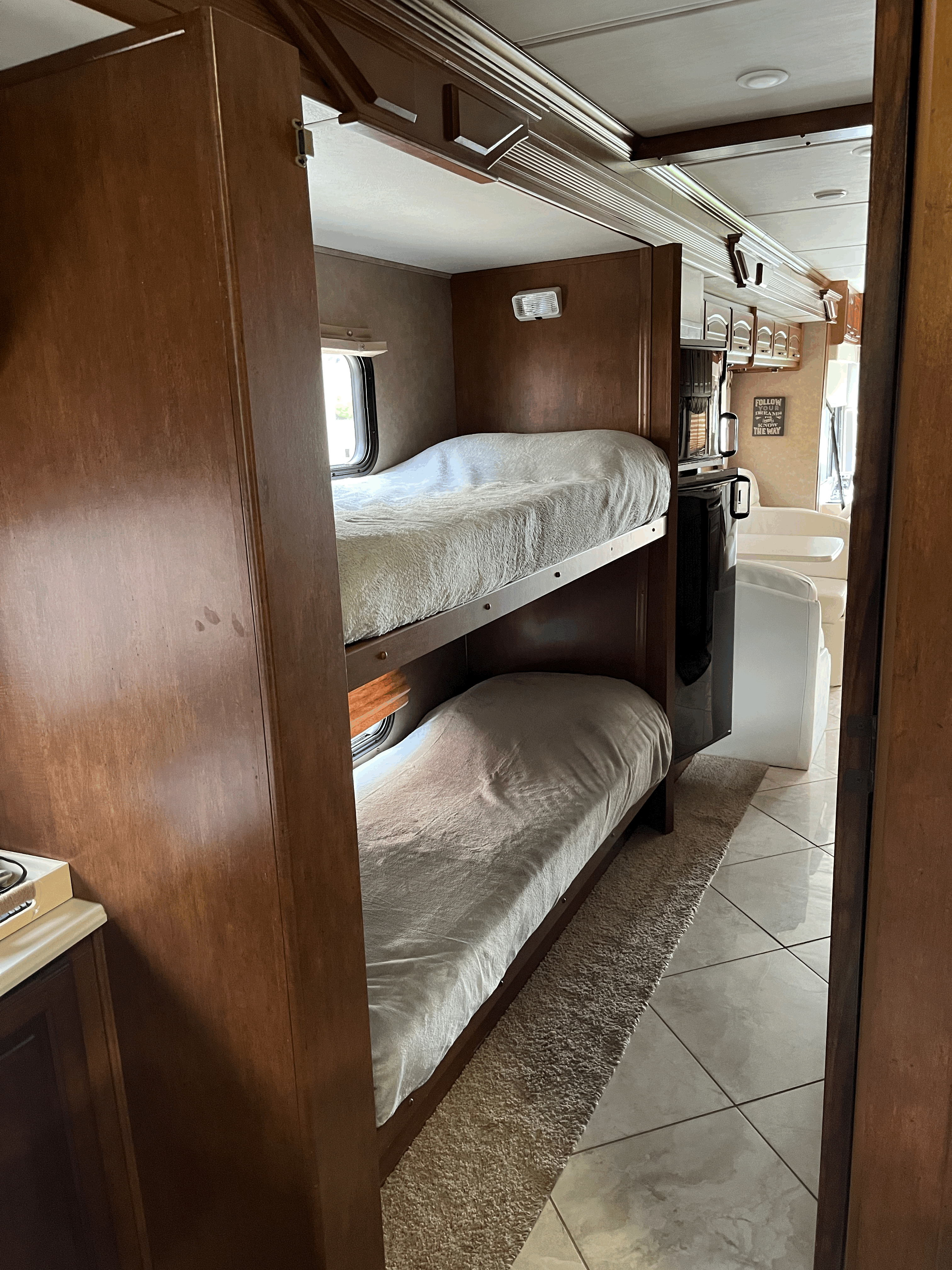 Inside this RV rental, stacked bunk beds are on the left, with a fridge and glimpse of the main living area on the right.. Forest River Coachmen Cross Country 2013
