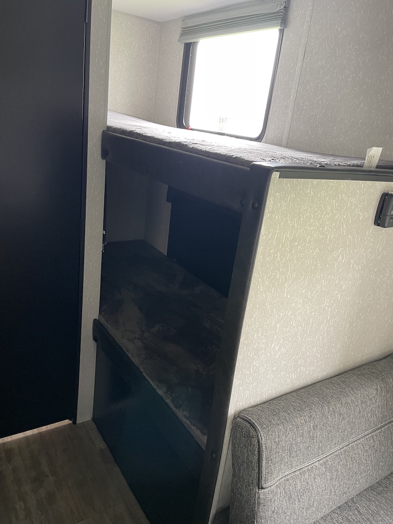 Inside an rv rental: functional bunk beds with a window and a sofa nearby, offering compact sleeping space.. Forest River Cherokee Wolf Pup 2022