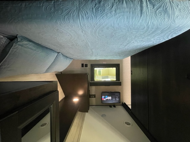 Cozy RV rental interior with a light blue bed, control panel, and dark cabinetry. Ideal for travel comfort.. Jayco 267 BHS F 2022