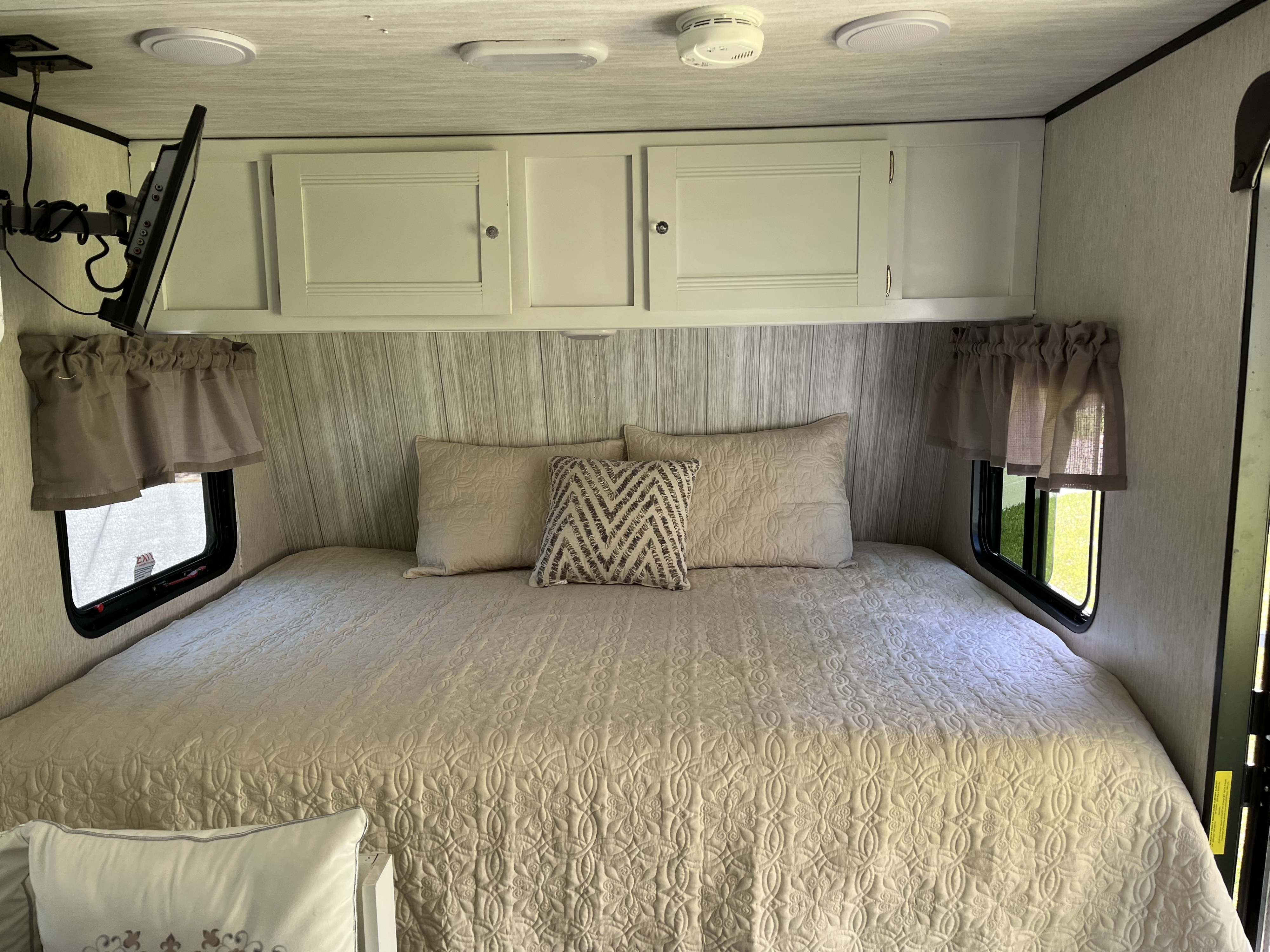 Cozy RV rental bedroom with quilted bed, overhead cabinets, and TV. Ideal for a comfortable getaway.. Heartland RVs Pioneer 2019