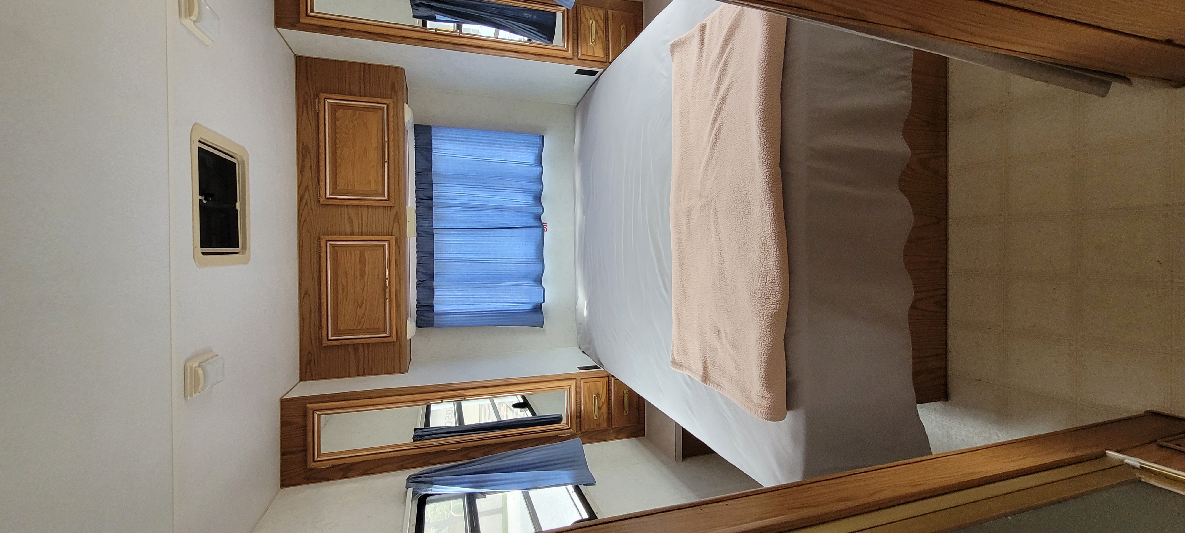 RV rental bedroom: a cozy interior with a neatly made bed, wood cabinets, and blue window blinds.. Fleetwood Tioga Arrow 1993