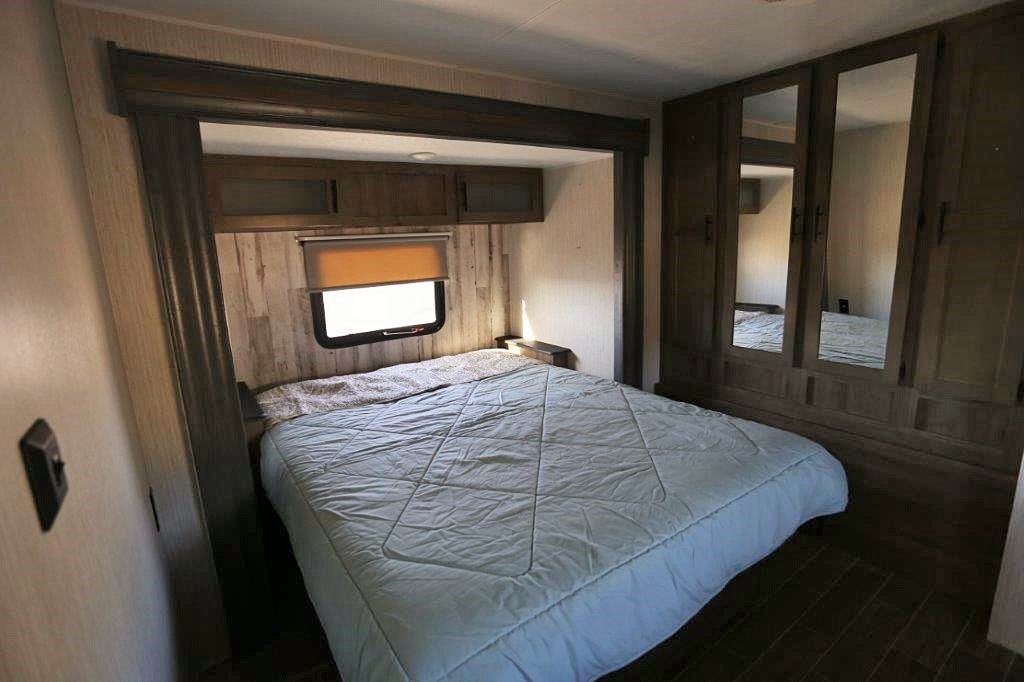 Clean RV rental bedroom with queen bed, window, overhead cabinets, and mirrored closet. Ready for your adventure.. Palomino Puma 31-RLQS 2021