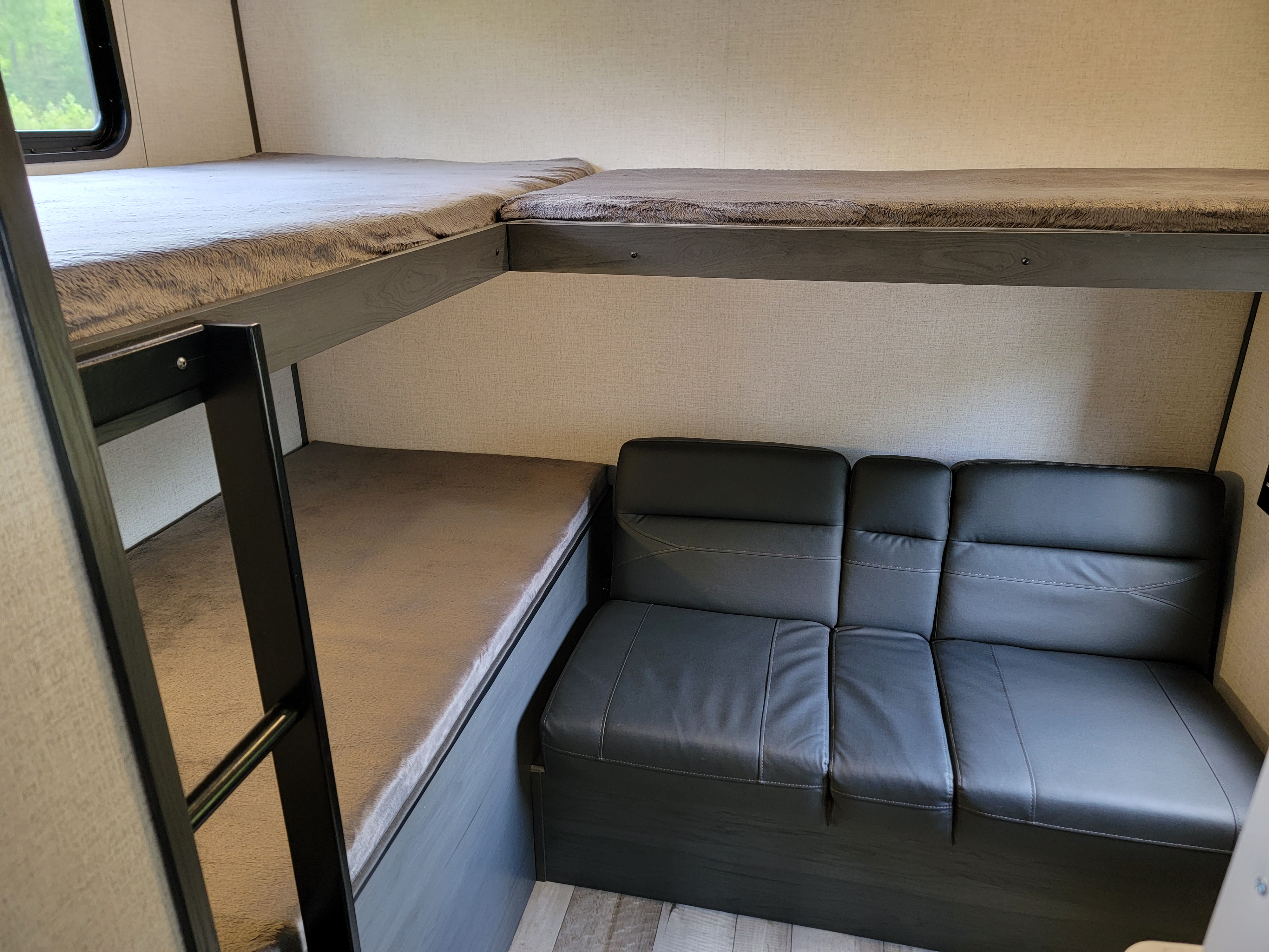 RV rental interior: two cozy bunk beds with gray blankets and a comfortable black sofa for relaxing.. Dutchman Aspen Trail 2022