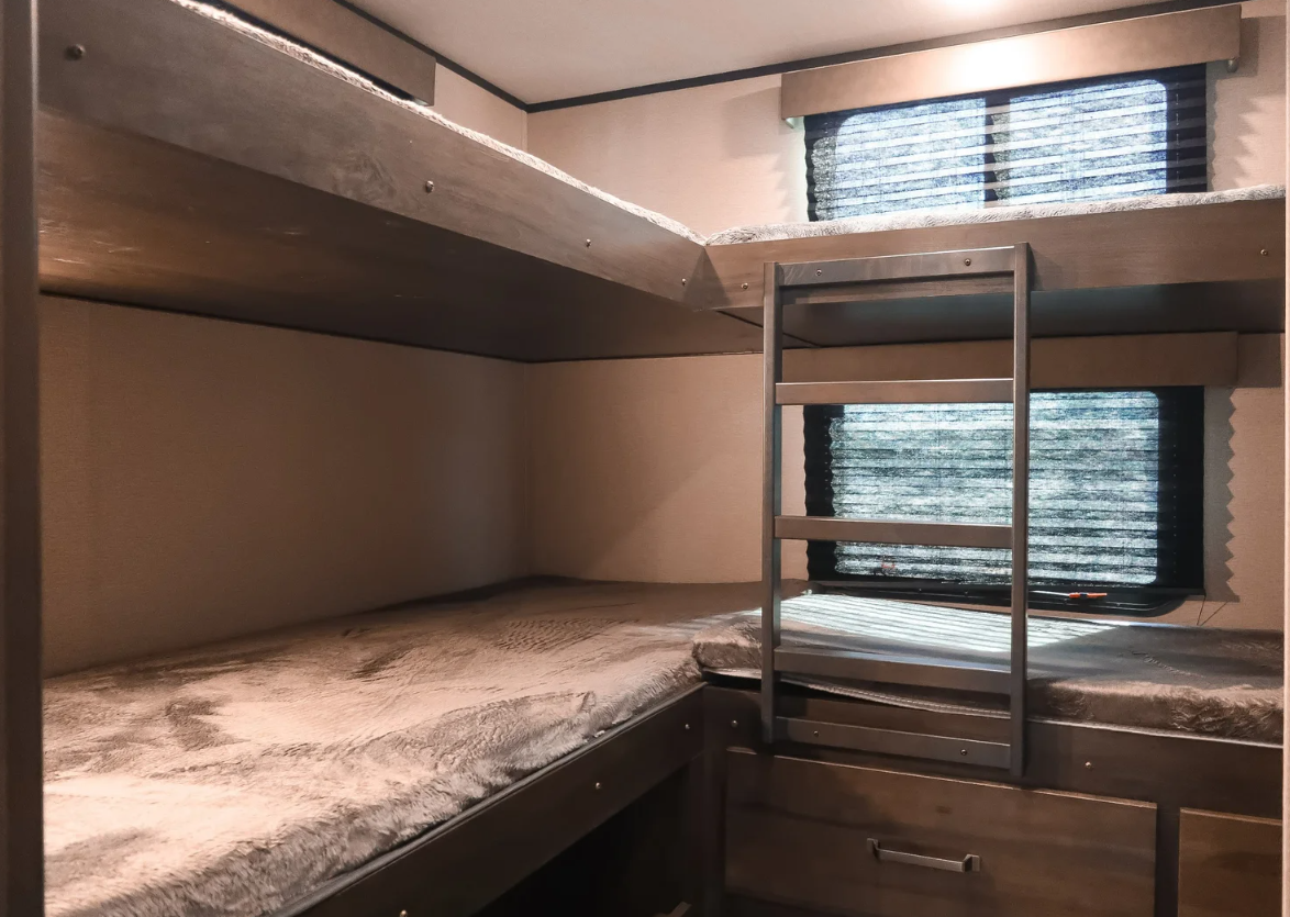 Cozy RV rental bunk room. Multi-level beds with ladder, plush bedding, and windows. Ideal for family adventures.. Grand Design Xplor 2022