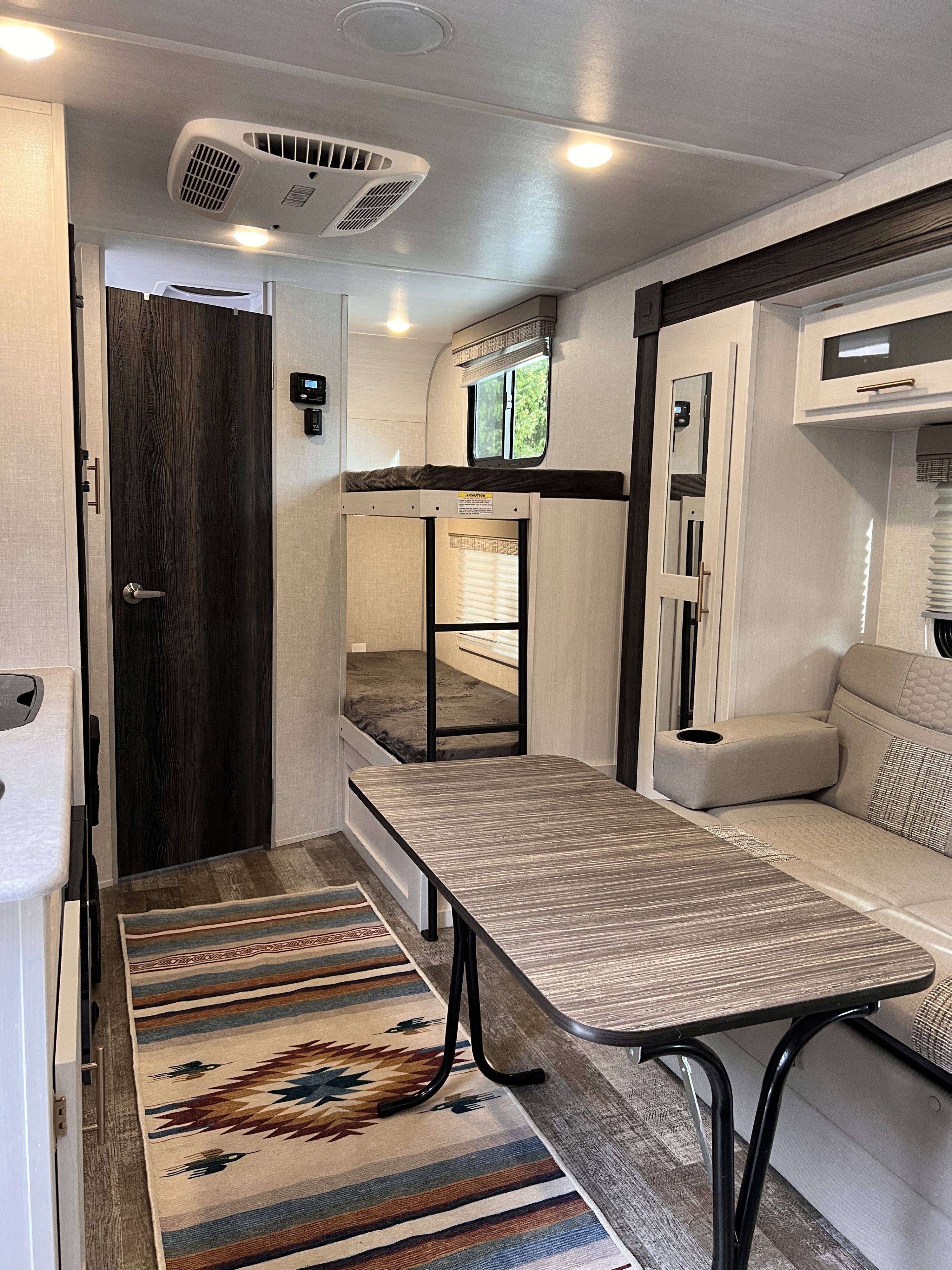 Inside an RV rental: a cozy interior featuring a dining table, comfortable bench seating, and practical bunk beds.. R-Pod Hood River Edition 2021
