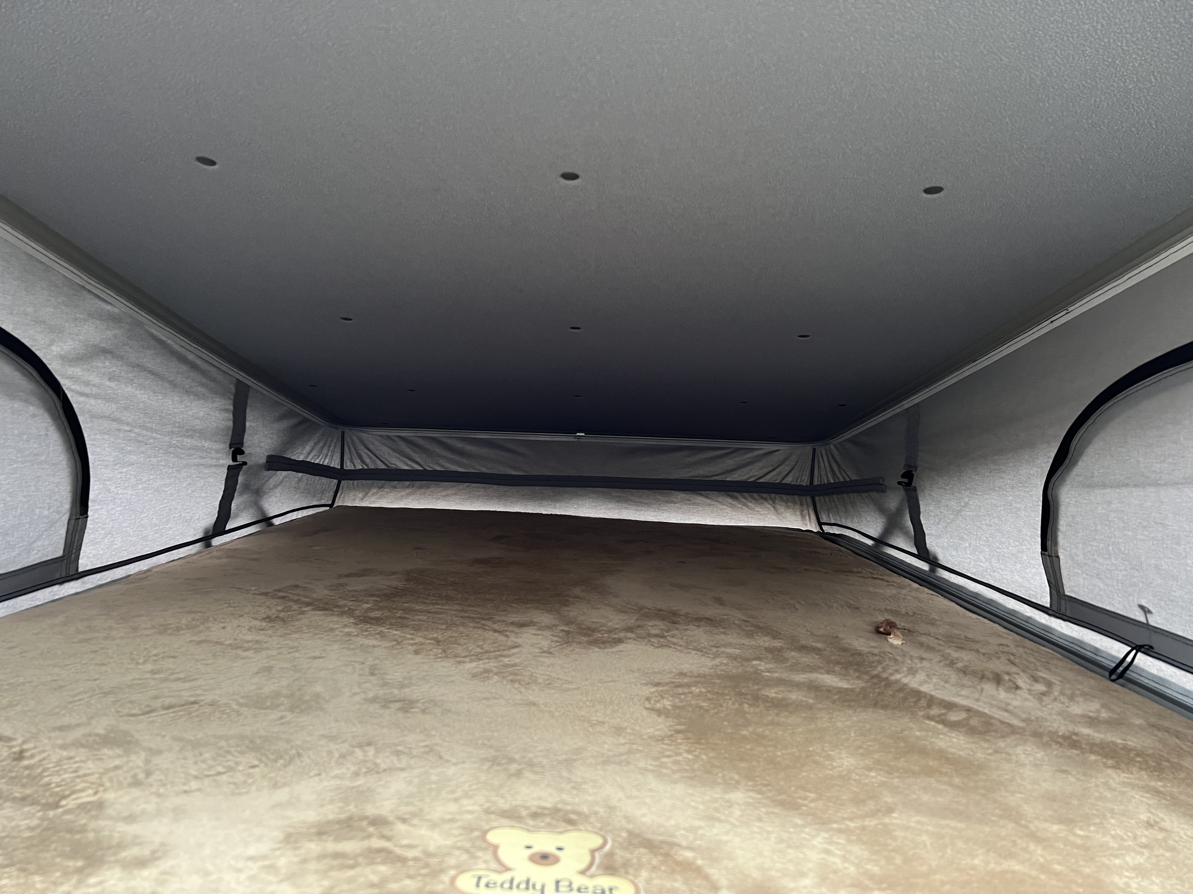 View inside an RV rental's pop-top sleeping area, featuring a soft, brown mattress and integrated ceiling lights.. Thor Motor Coach Sequence 2022