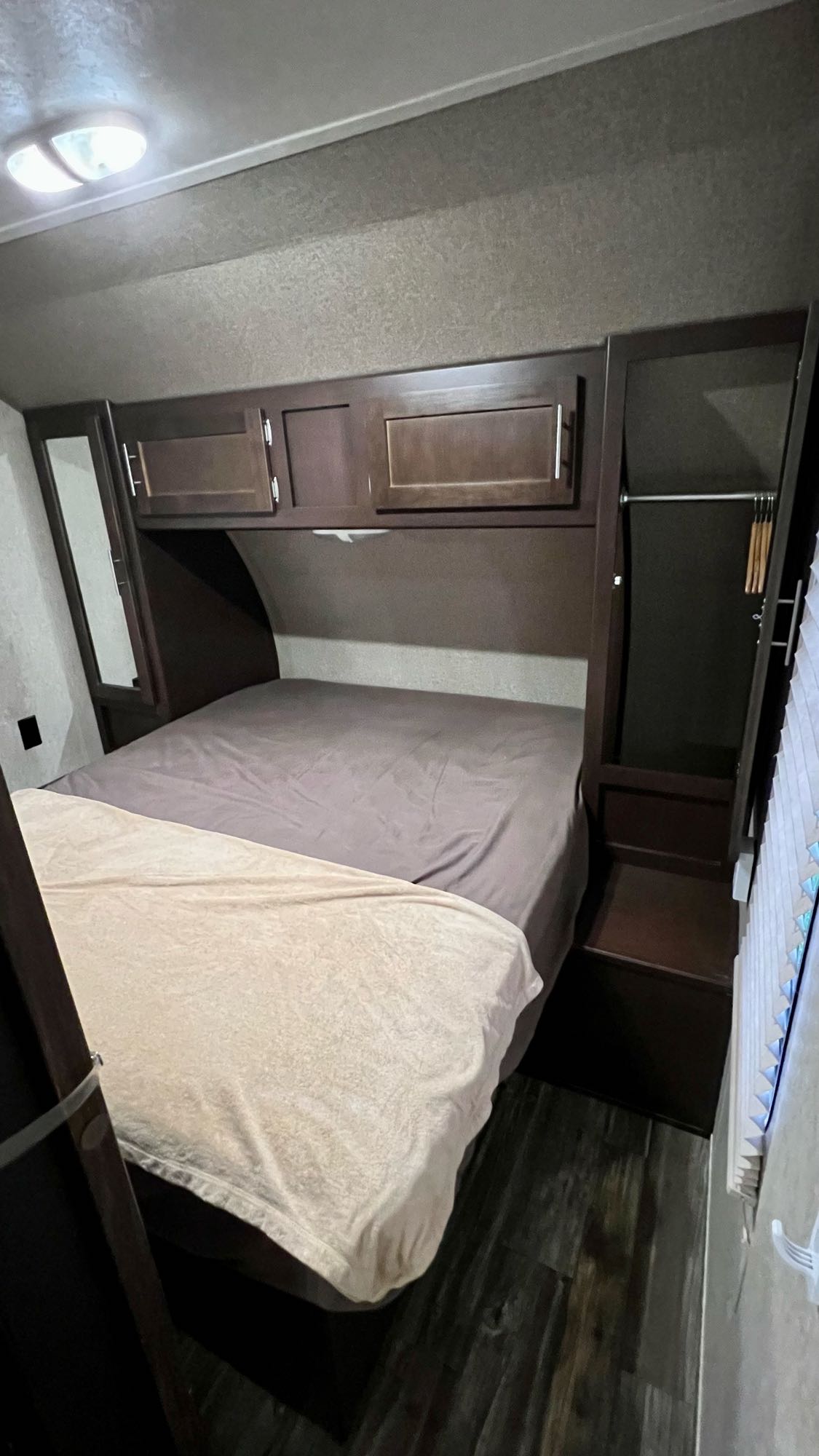 Inside an RV rental, this cozy bedroom features a comfortable bed, convenient overhead storage, and a built-in wardrobe.. Forest River Cherokee 2015